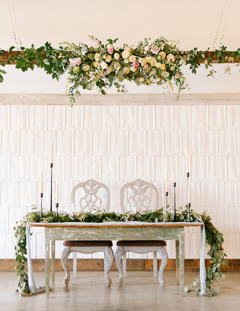 sweetheart table with draped greenery and candles