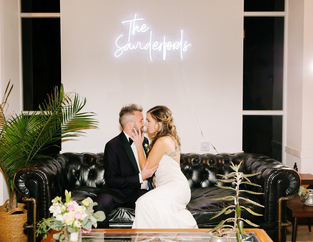 newlyweds pose under neon light of married name