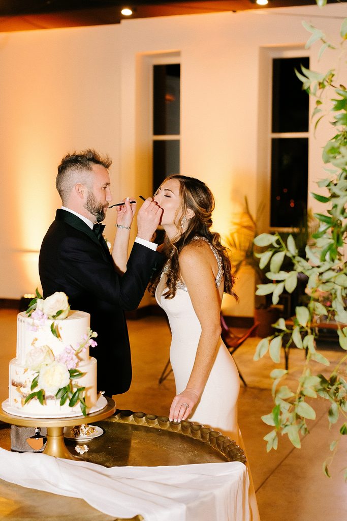 groom feeds bride cake during reception at The Meadows Raleigh