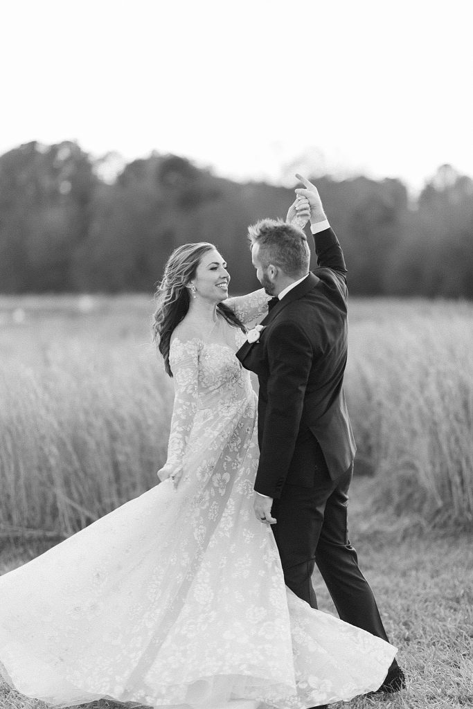 newlyweds dance in field at sunset