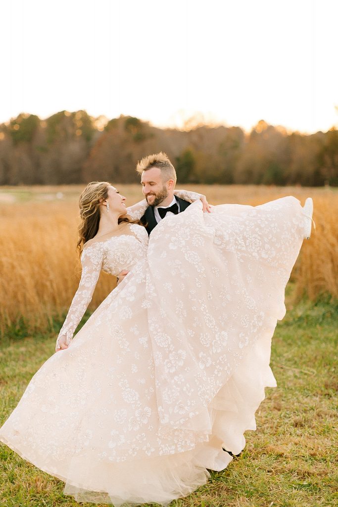 groom lifts bride up showing off wedding gown