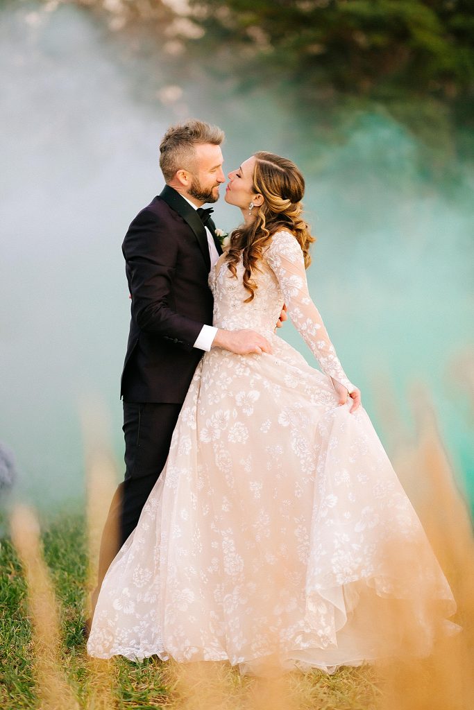 newlyweds pose in front of green smoke bomb