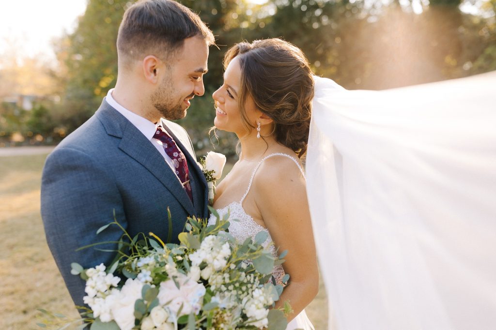 newlyweds look at each other with veil floating