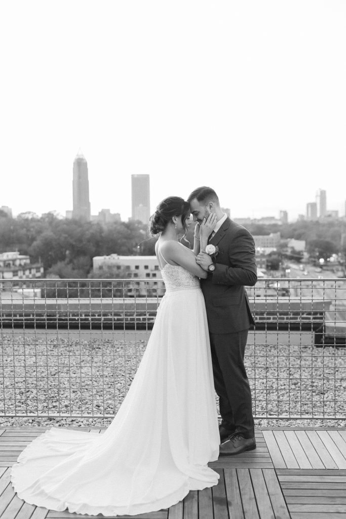 bride and groom stand nose to nose on rooftop in Downtown Atlanta