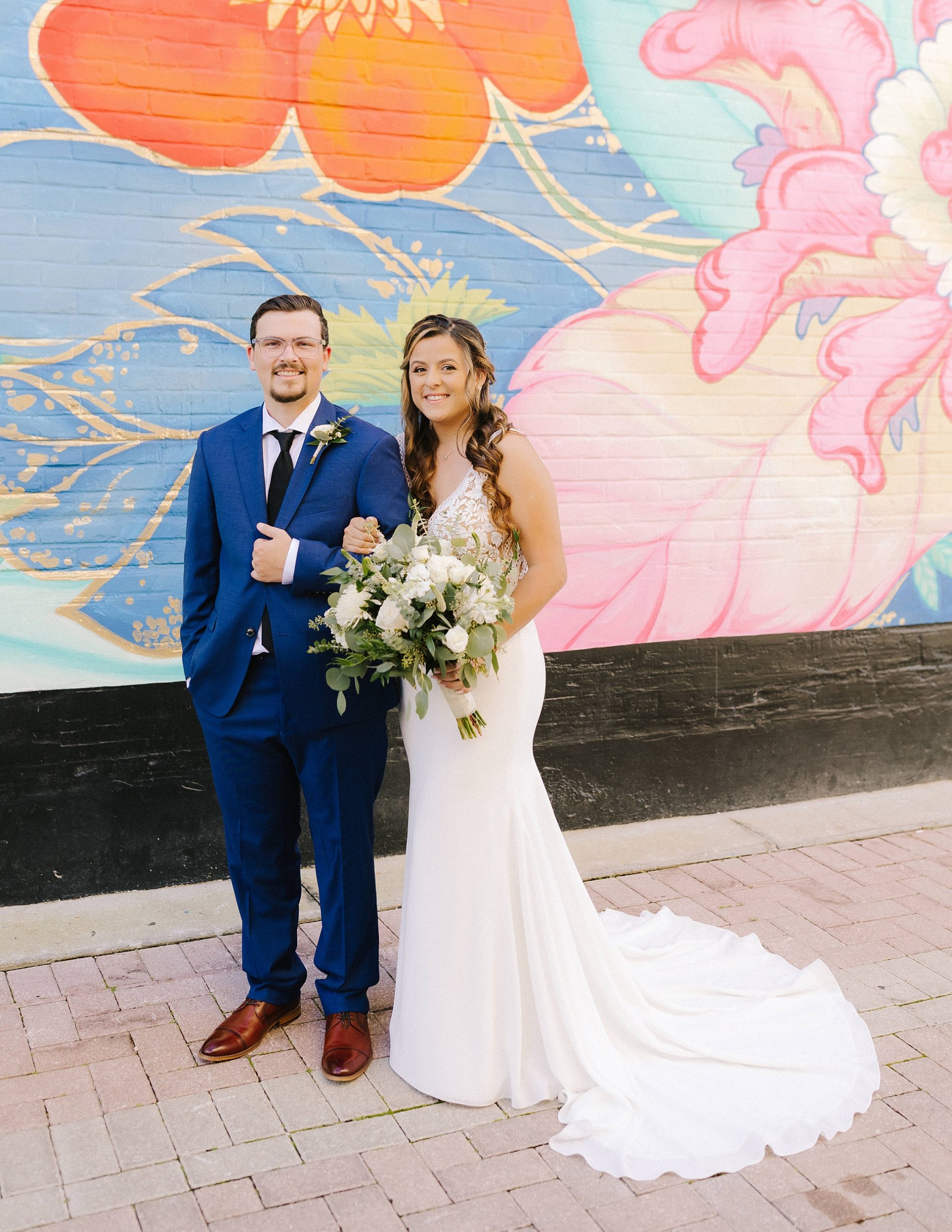 bride and groom pose in front of colorful mural in downtown Lakeland
