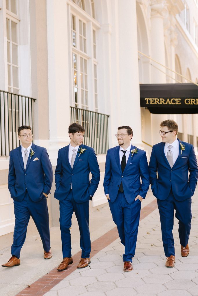 groom in navy suit poses with three groomsmen in navy suits