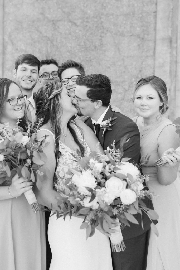 bridal party cheers for newlyweds kissing