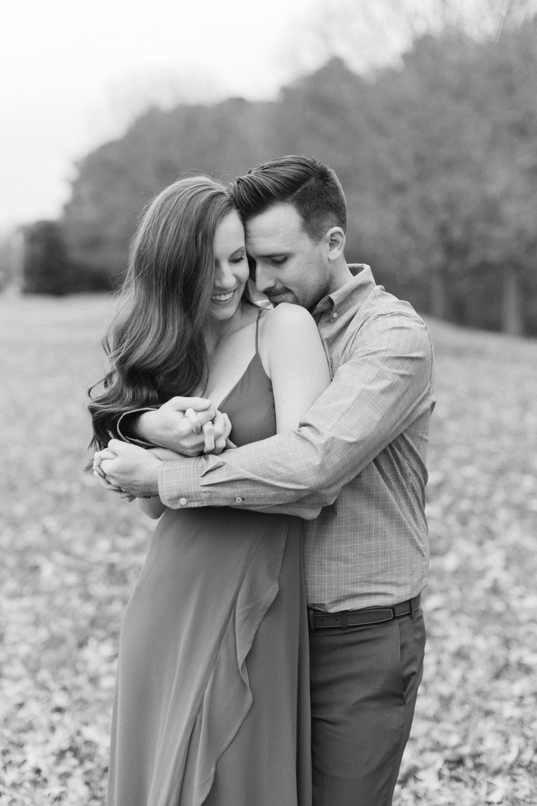 groom hugs fiancee from behind during fall engagement photos