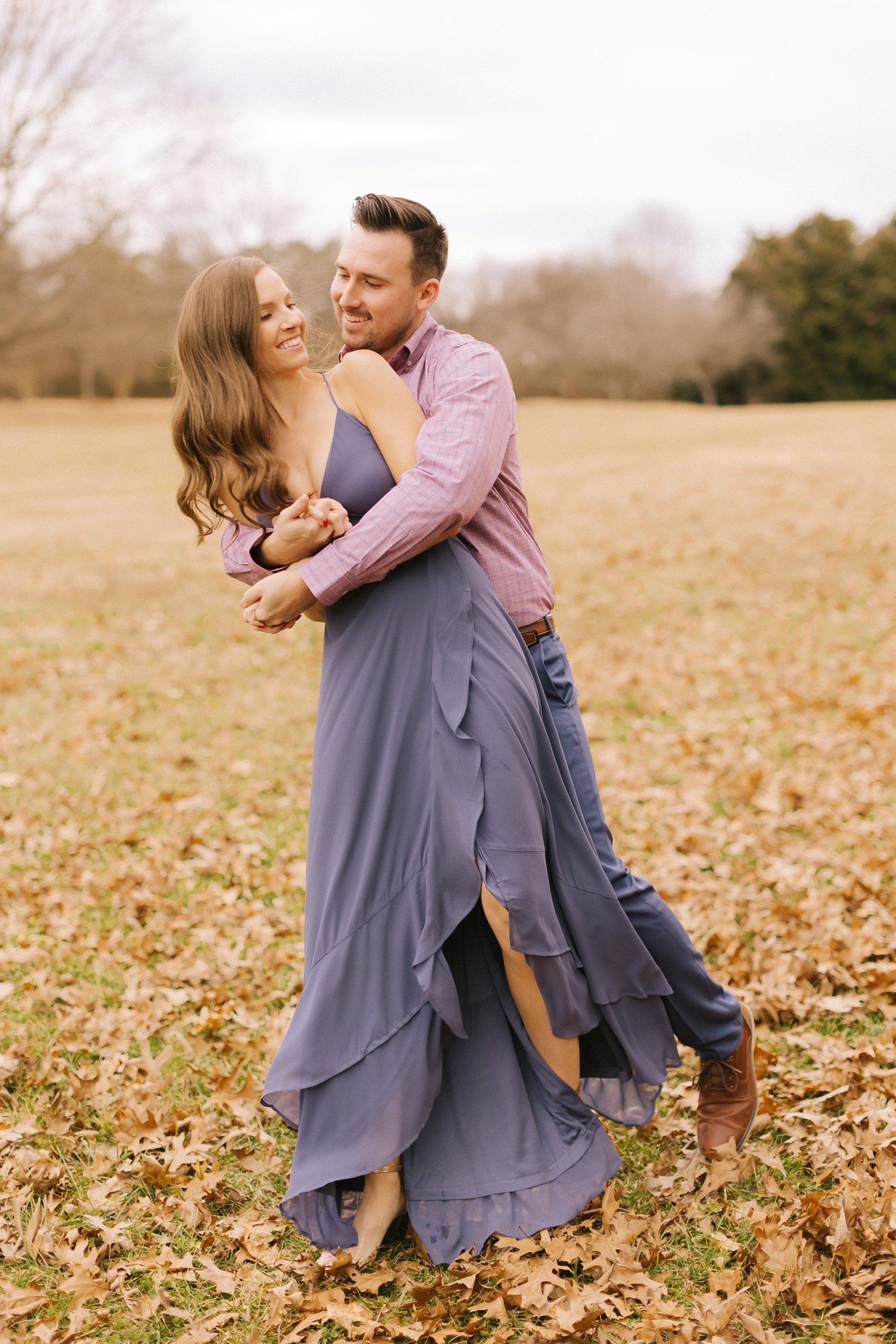 bride and groom hug and lean during fall engagement photos in NC
