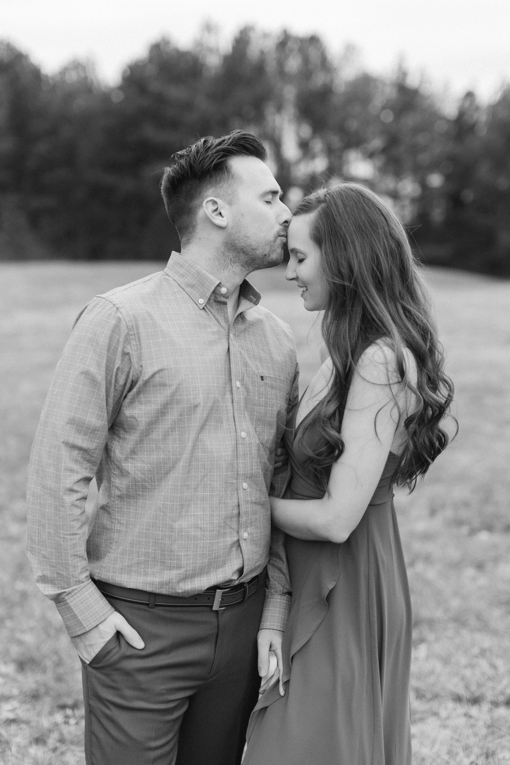 groom kisses fiancee's head during fall Jetton Park engagement photos