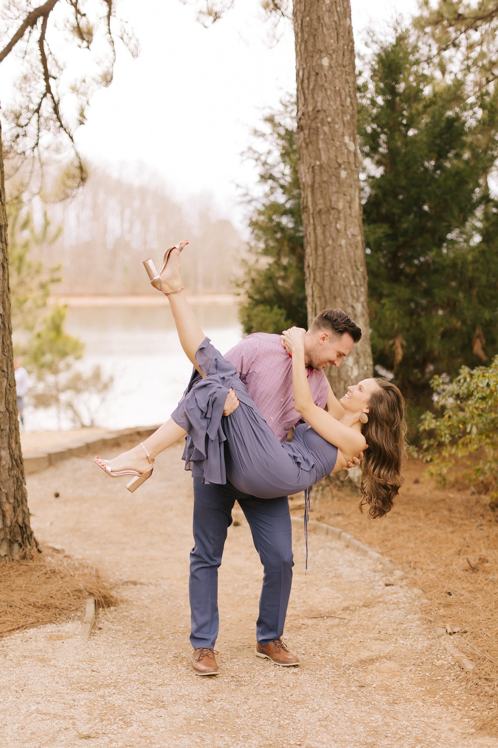groom holds and dips bride with her foot in the air during fall engagement session