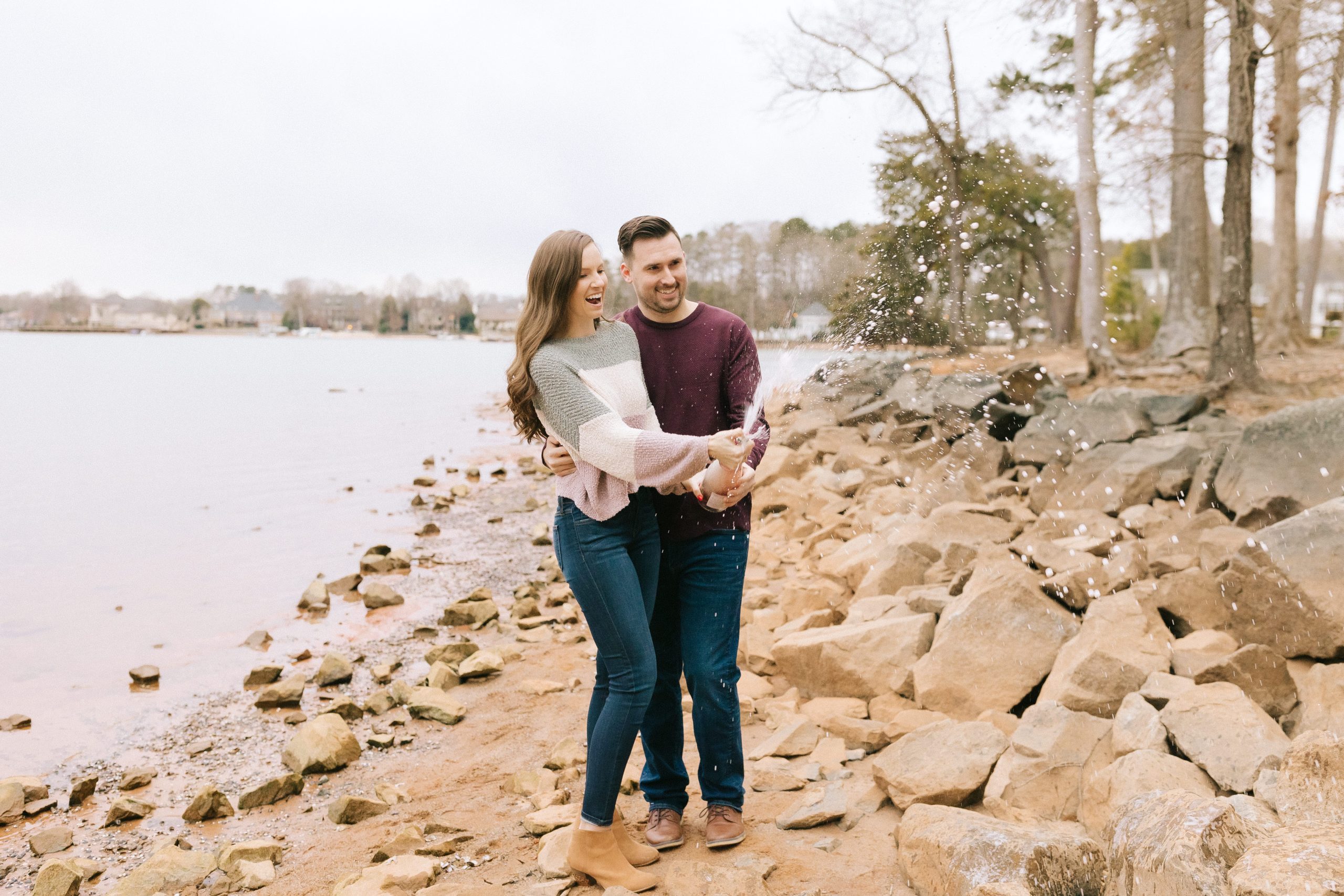 couple pops champagne at their engagement session with winston salem photographer chelsea renay