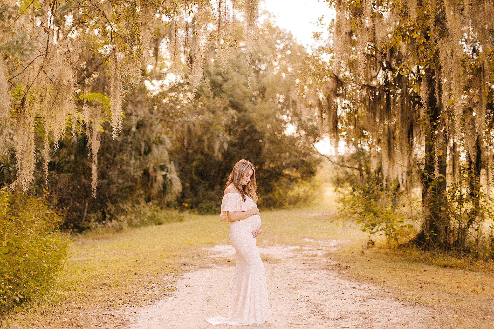 mom in pale pink gown holds baby belly during NC maternity photos