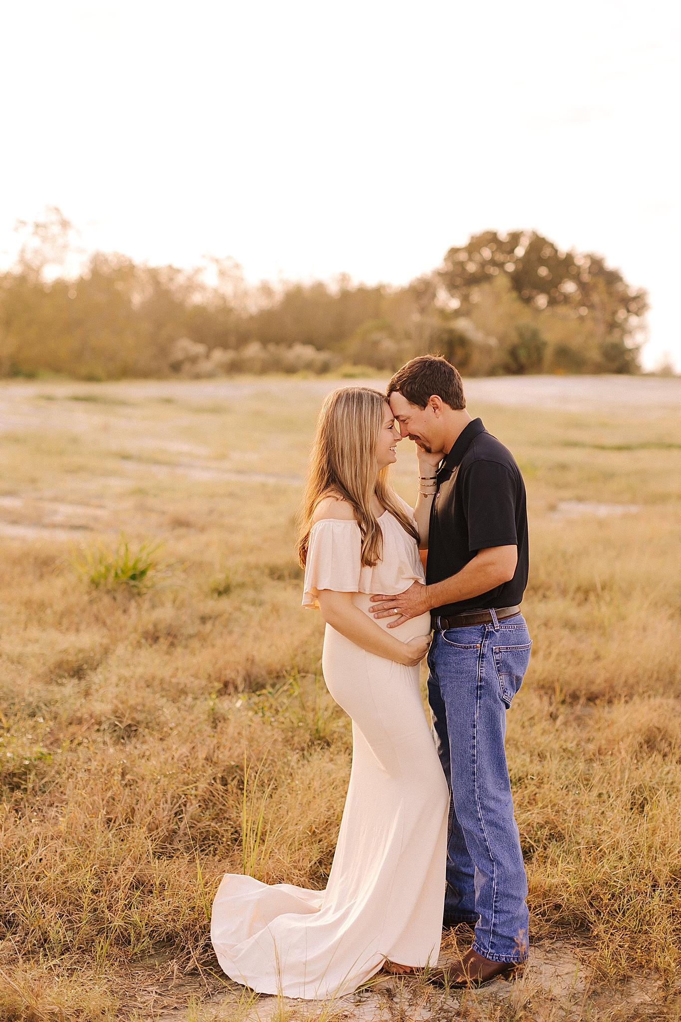 mom and dad stand nose to nose during NC maternity photos in field