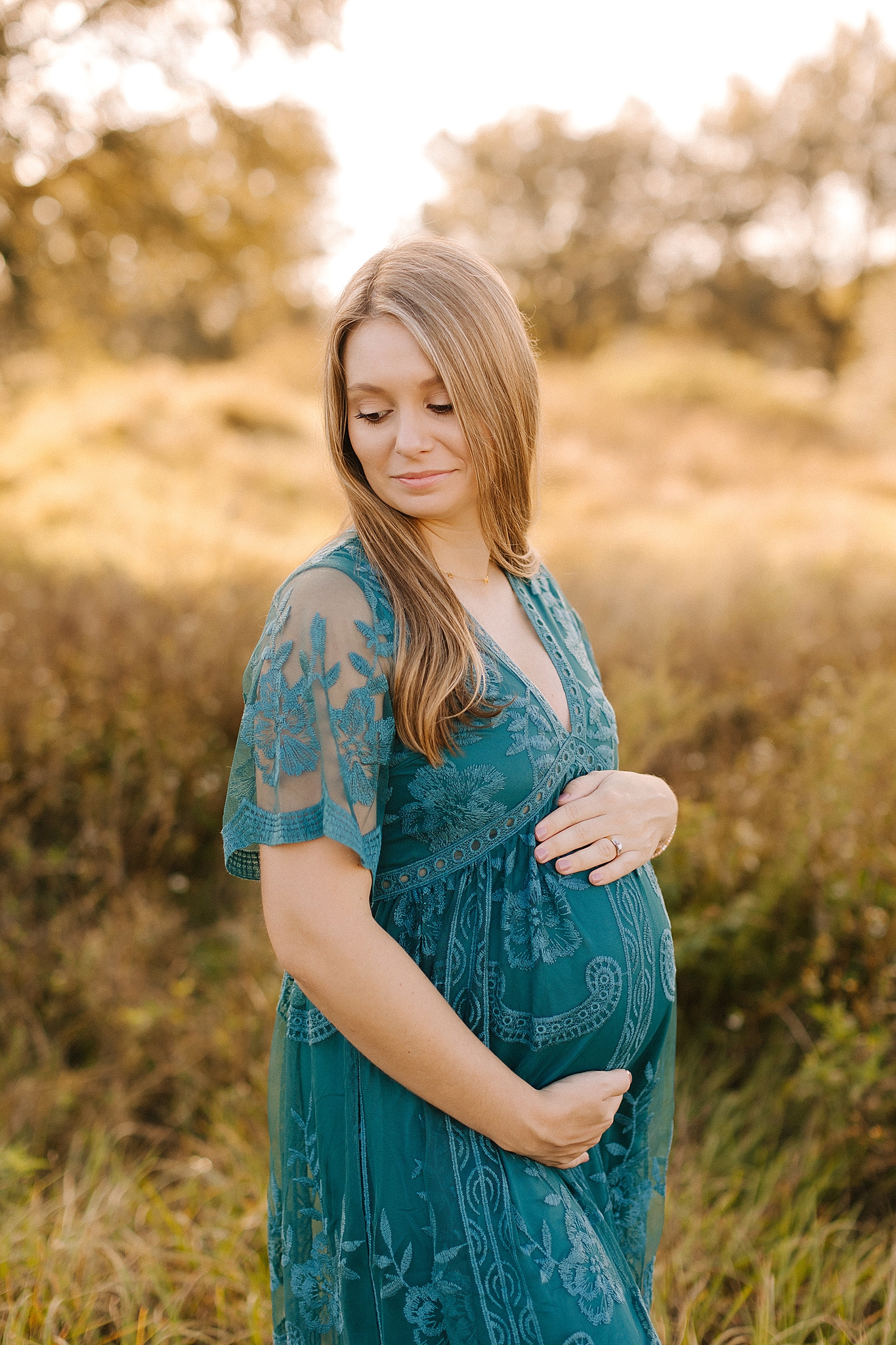 expecting mother holds belly during maternity photos in field