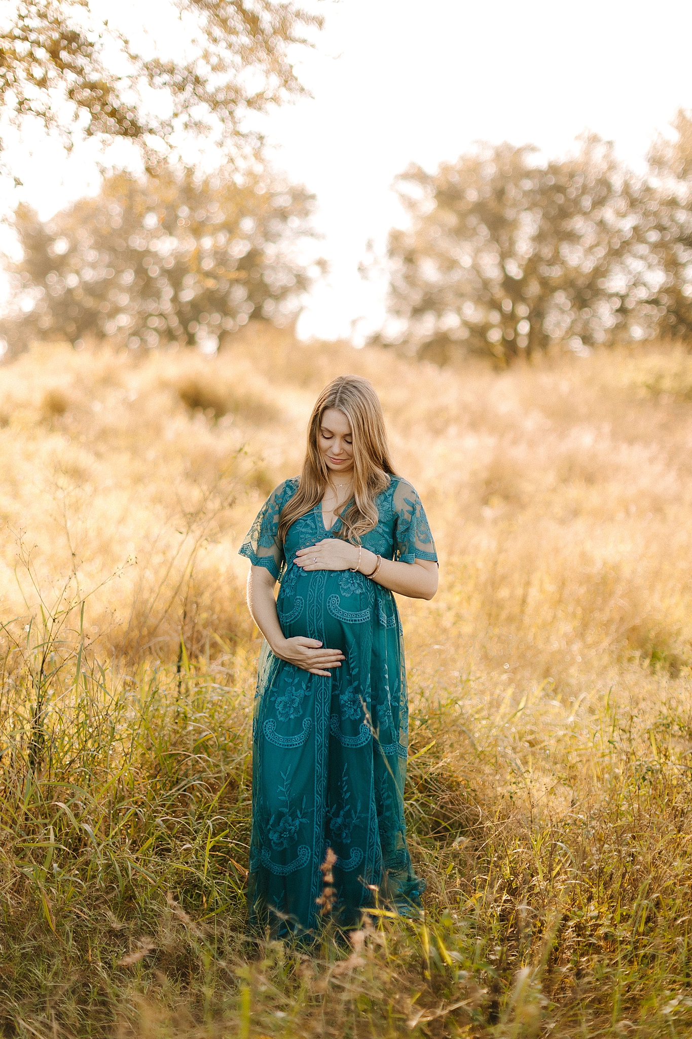 expecting mother holds baby belly in field