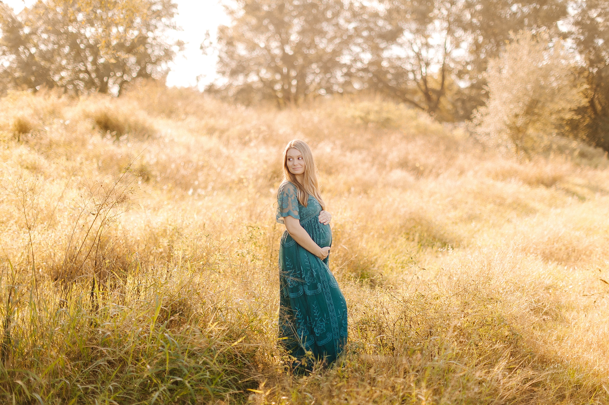 mom hold baby belly standing in field during Winston Salem maternity photos