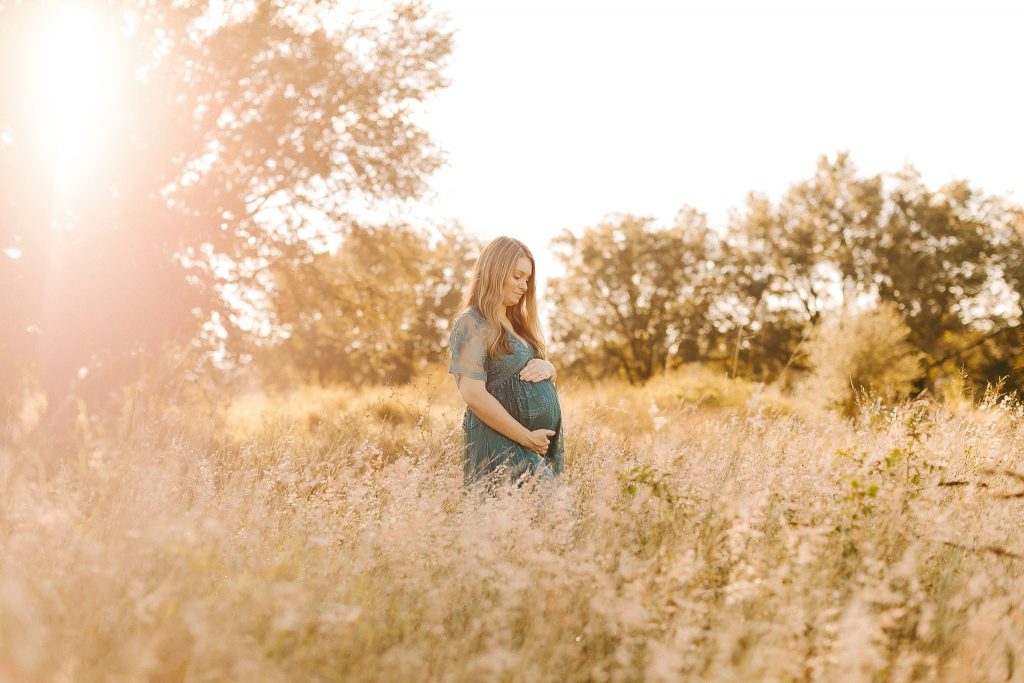mom looks down at belly during Winston Salem maternity photos