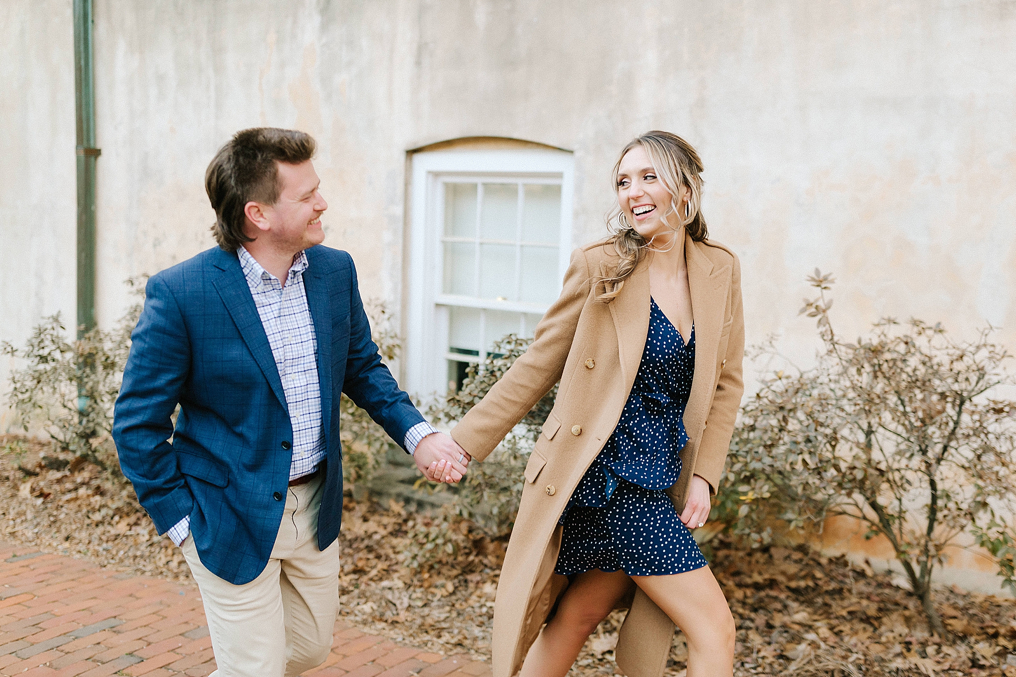 engaged couple walks by historic building in Downtown Winston Salem