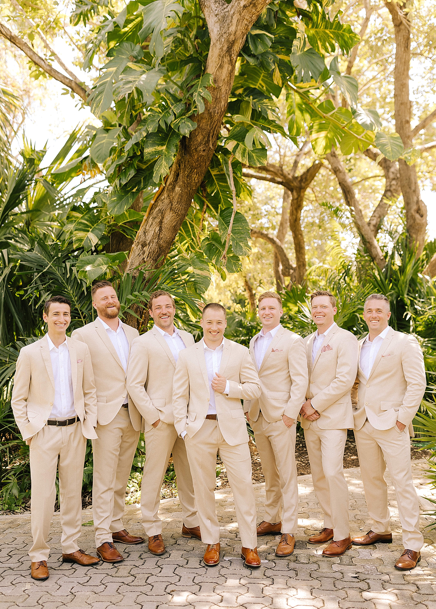 groom poses with groomsmen in tan suits