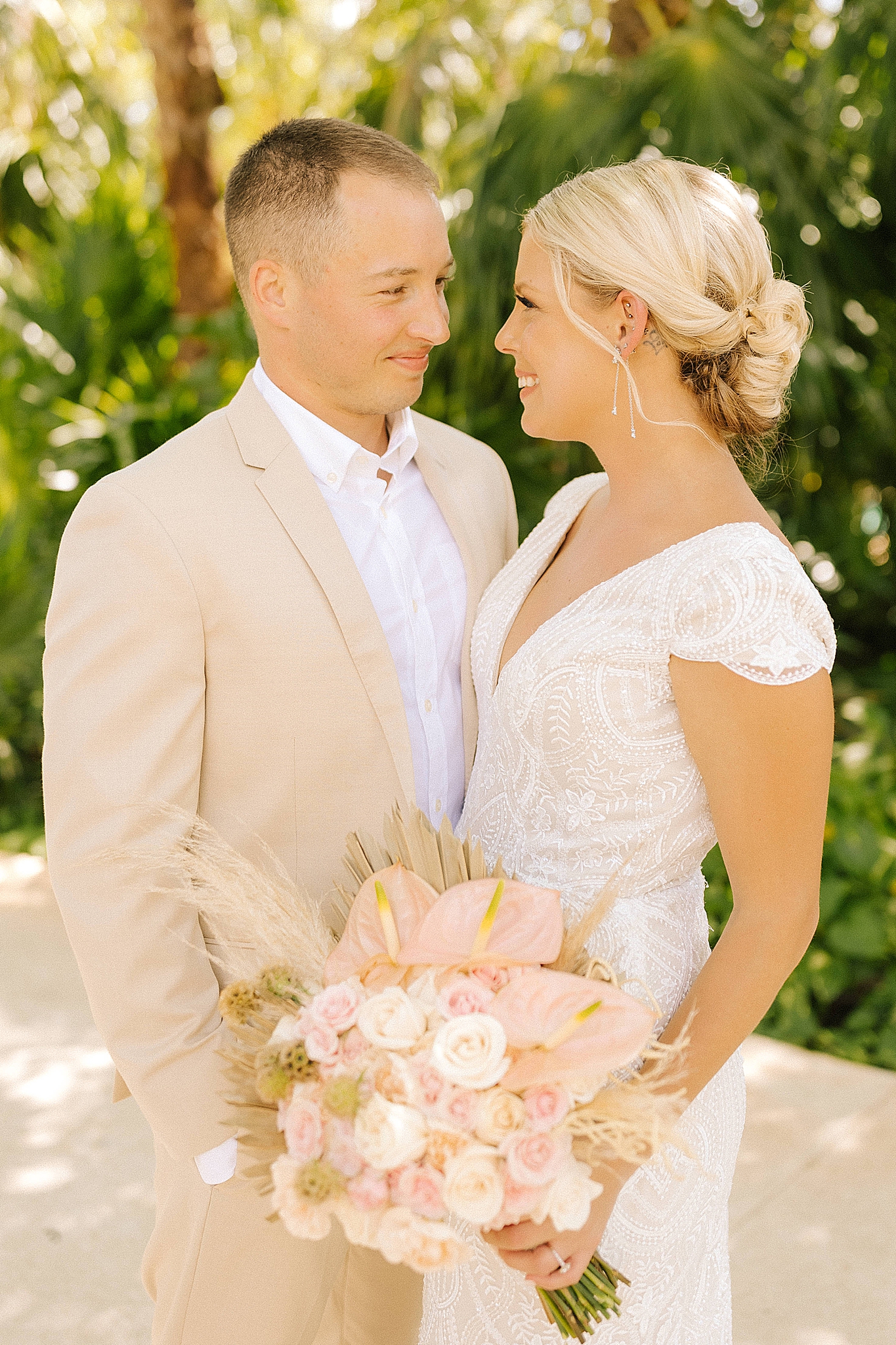 newlyweds pose by palm trees during Playa Del Carmen Destination Wedding