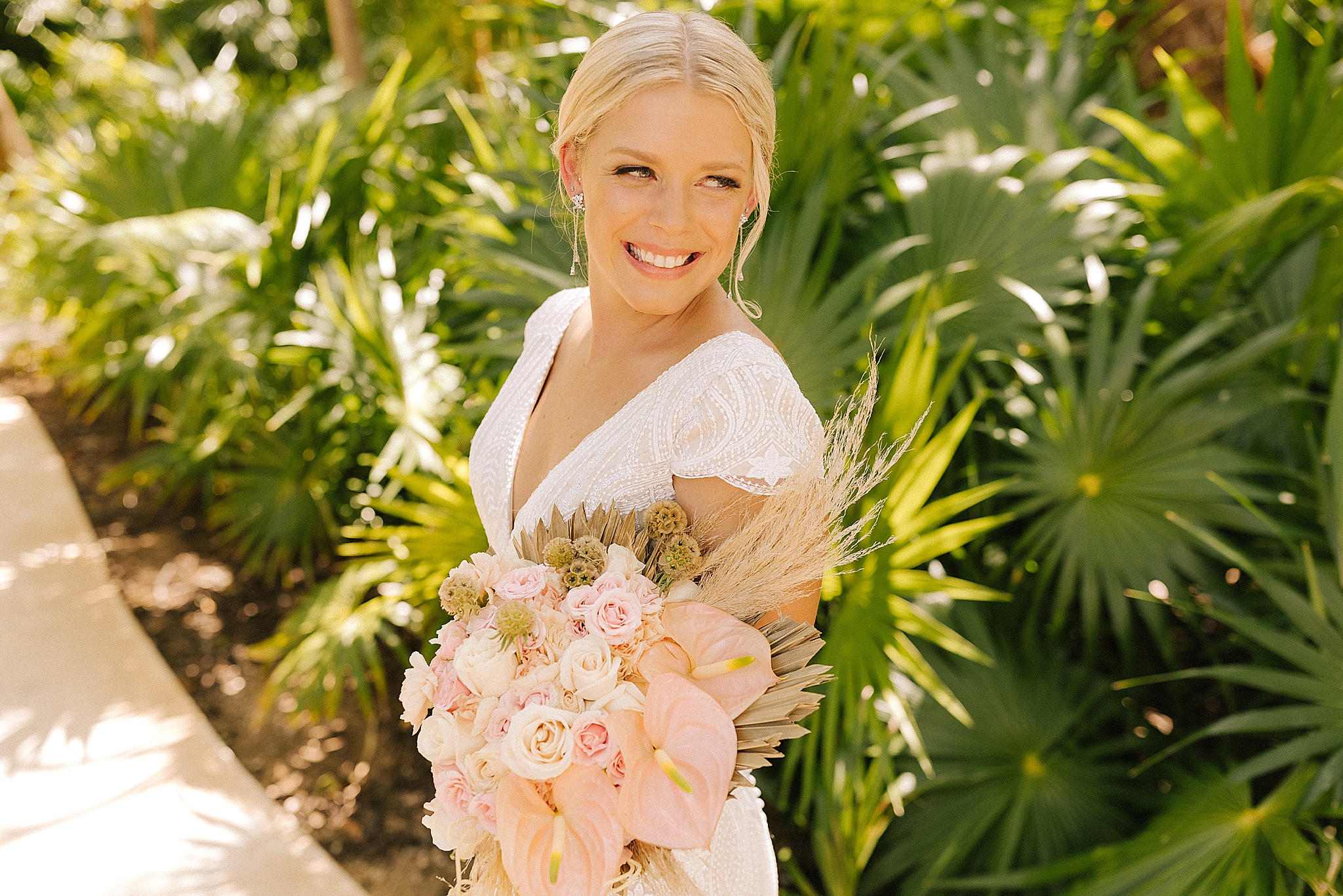 bride holds bouquet of pink tropical flowers in Playa Del Carmen