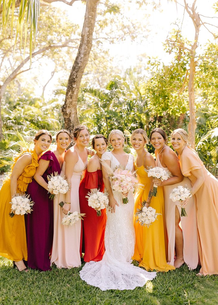 bridesmaids in mismatched gowns pose with bride for Playa Del Carmen destination wedding