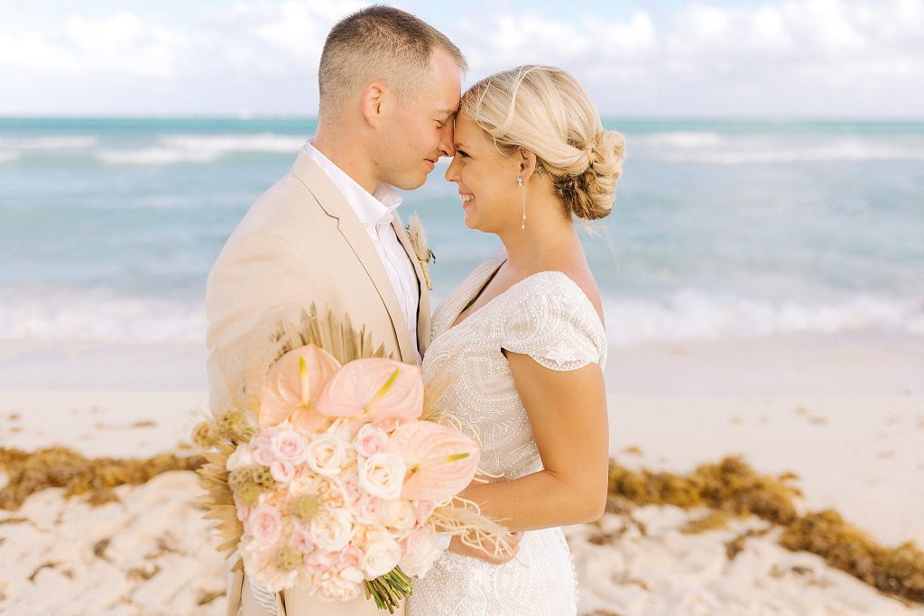 bride and groom stand nose to nose on Playa Del Carmen beach