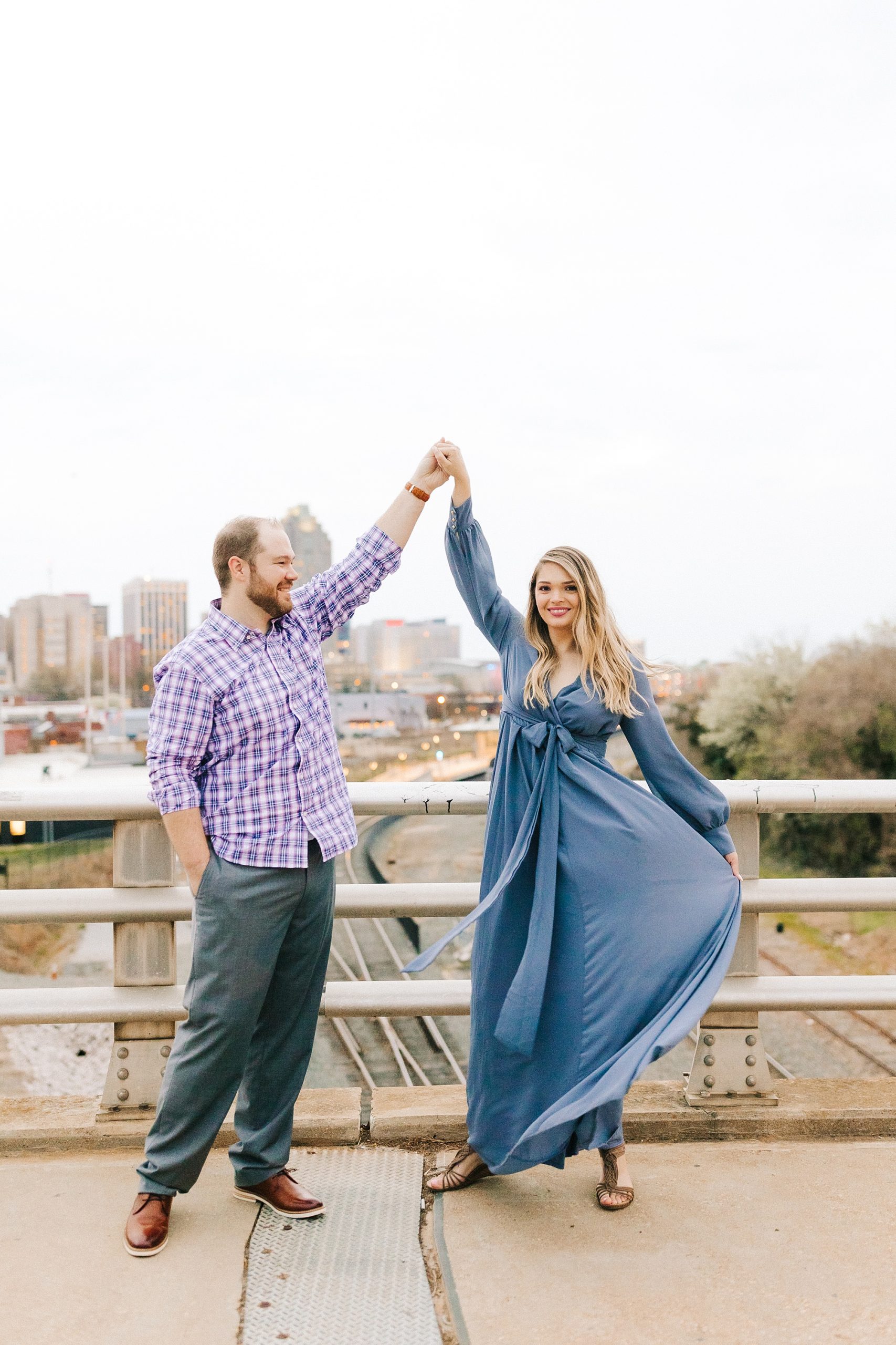 groom twirls bride during Downtown Raleigh engagement photos 