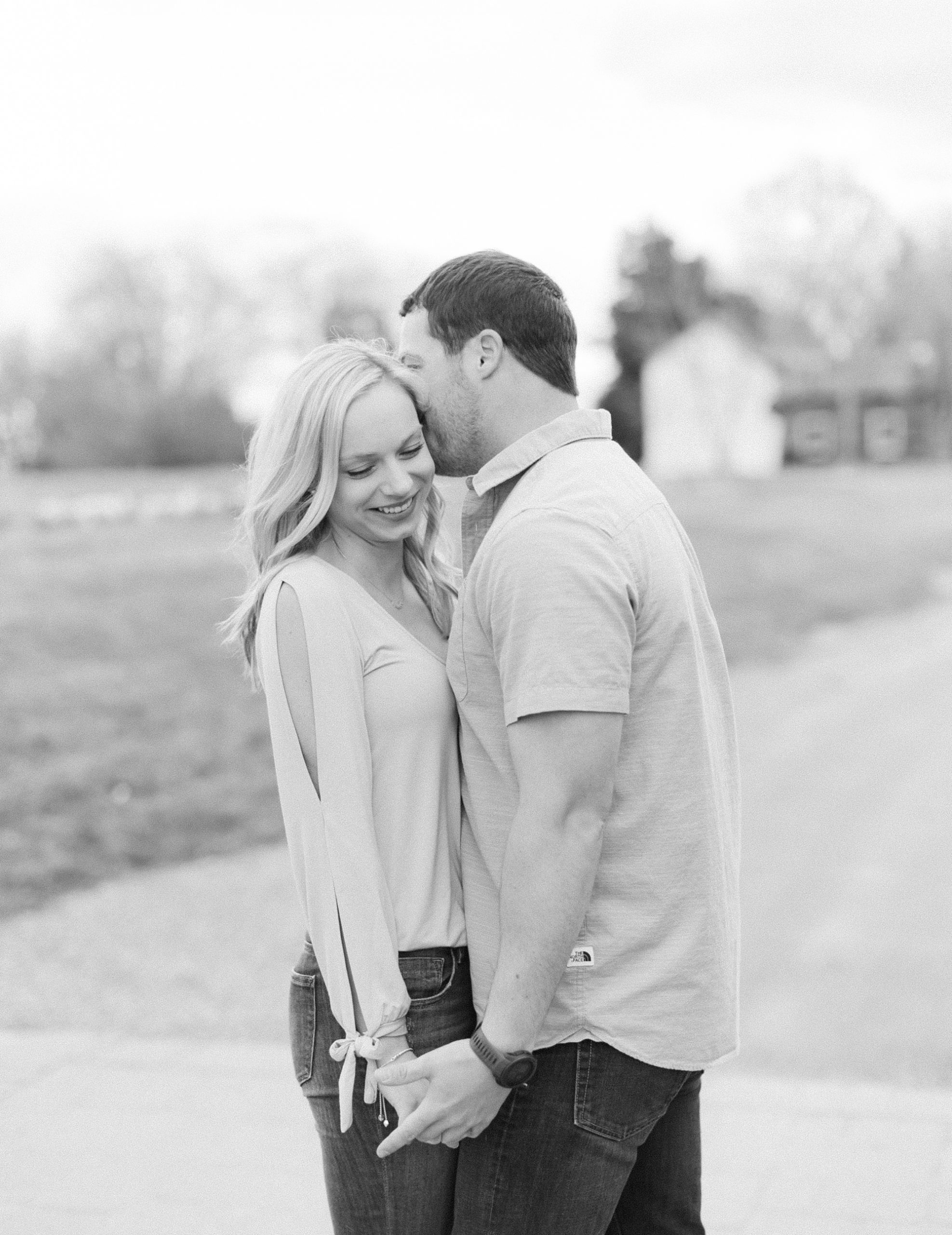 groom whispers in bride's ear during Summerfield Farms engagement session