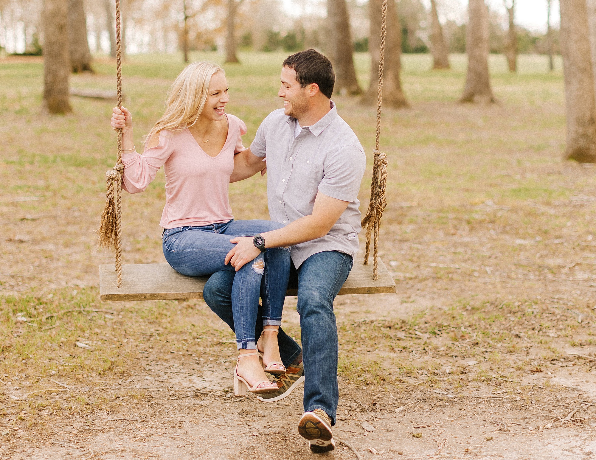 engaged couple sits on wooden swing in Greensboro NC