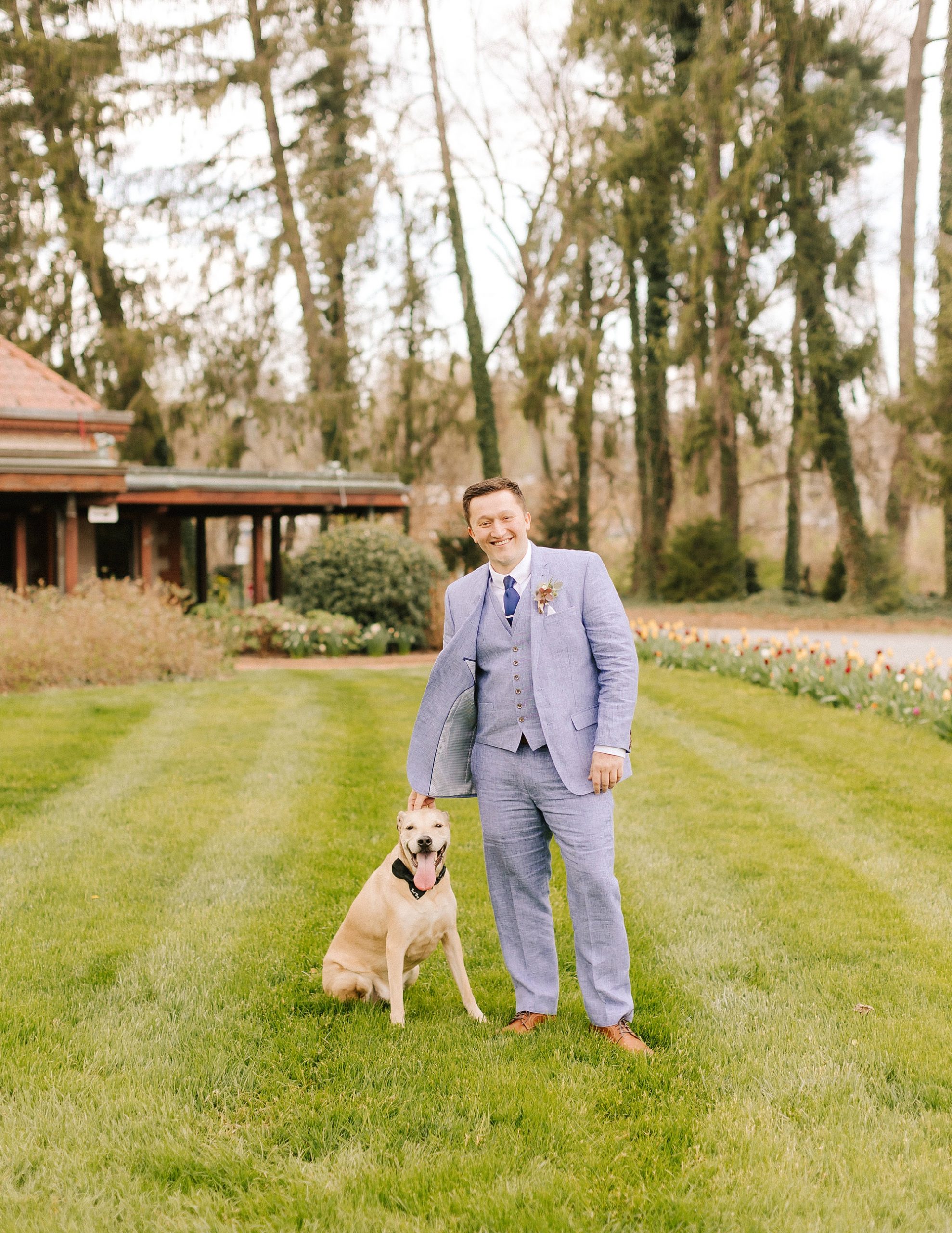 dog poses in garden with groom before elopement in Asheville NC 