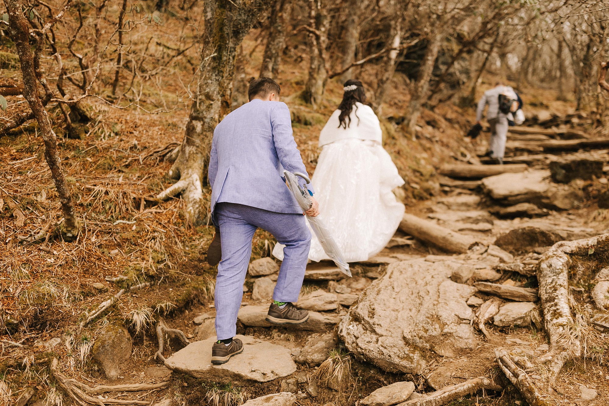 bride and groom climb up mountainside for elopement ceremony 
