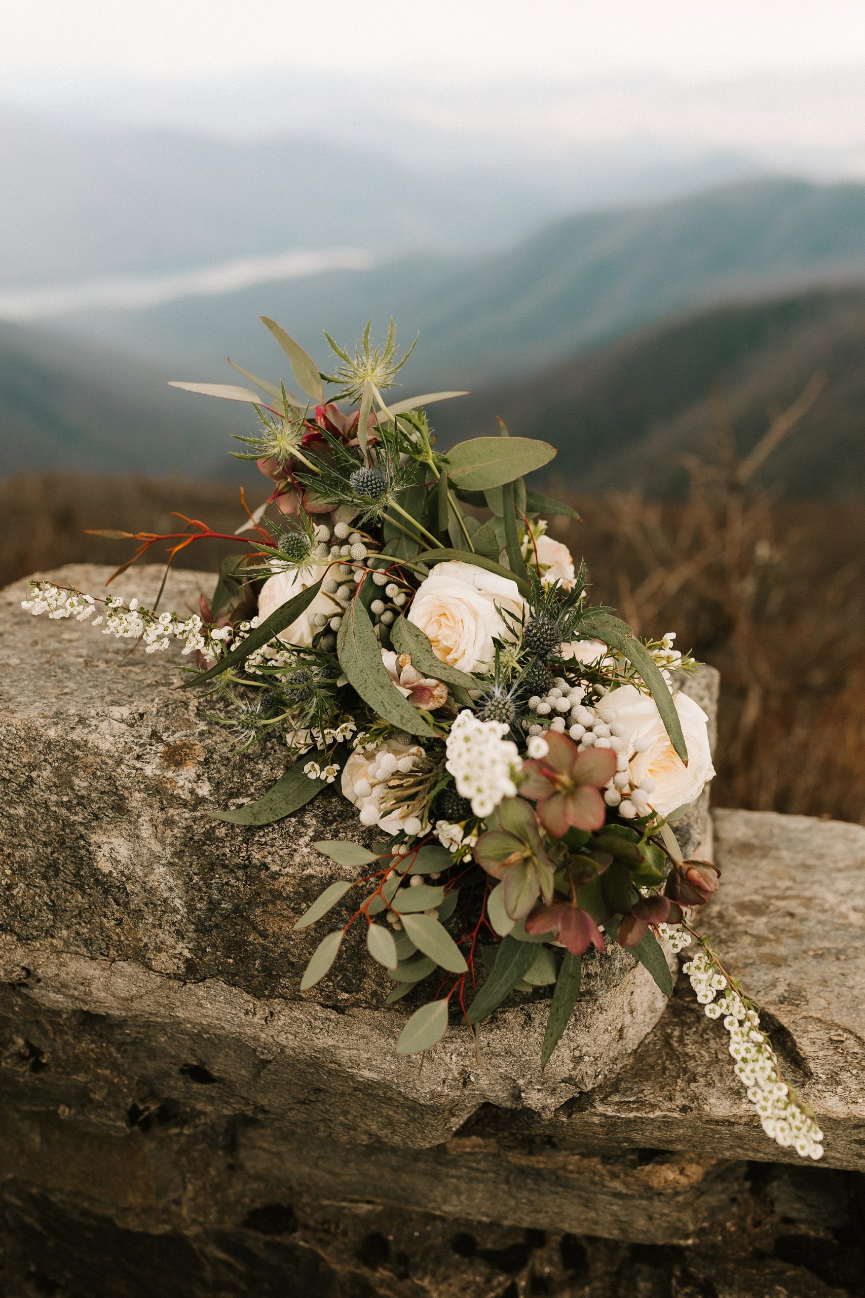 bride's bouquet sits on rocks on mountainside 