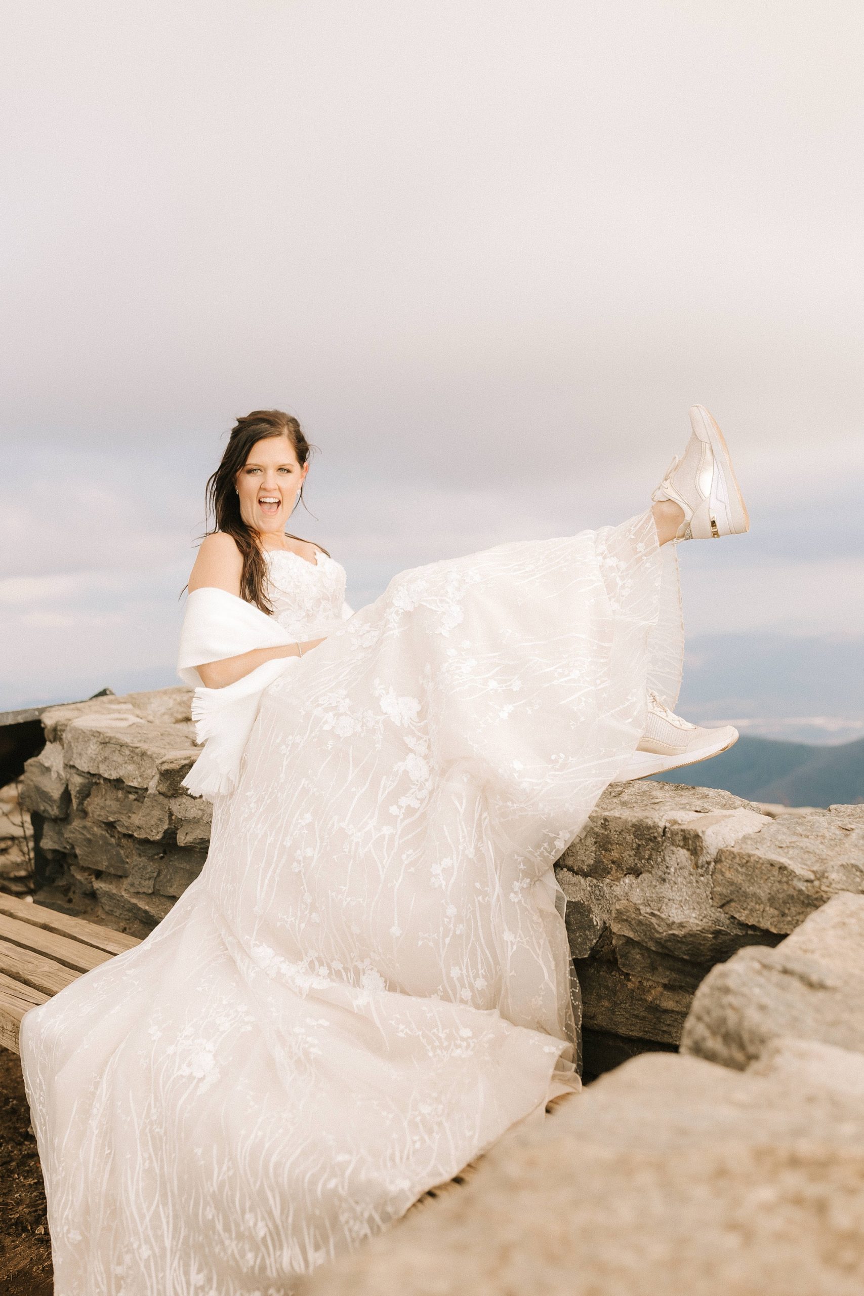 bride shows off tennis shoes on mountaintop 