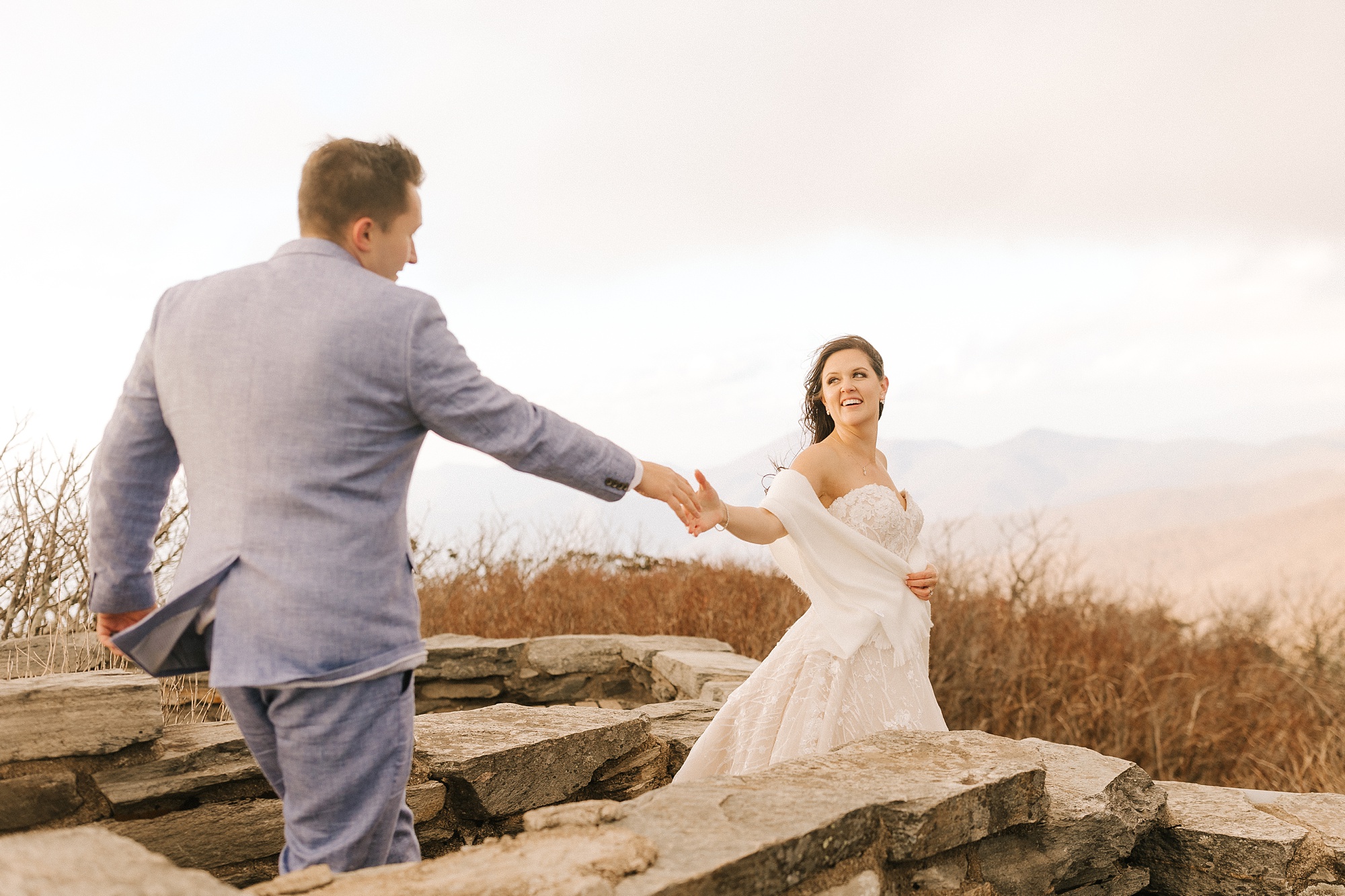 bride leads groom down path on mountaintop 