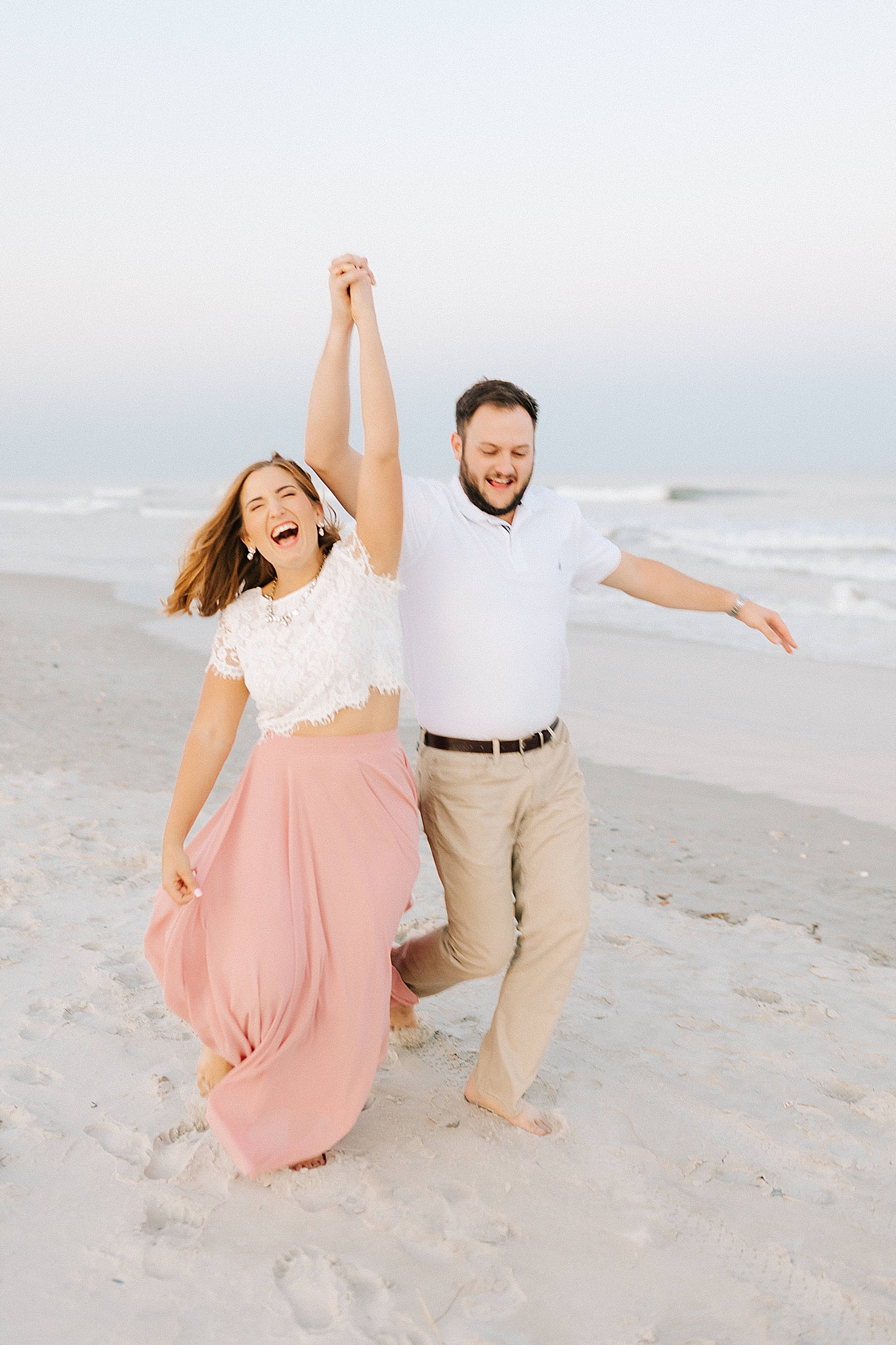 couple laughs and runs on beach during NC engagement photos