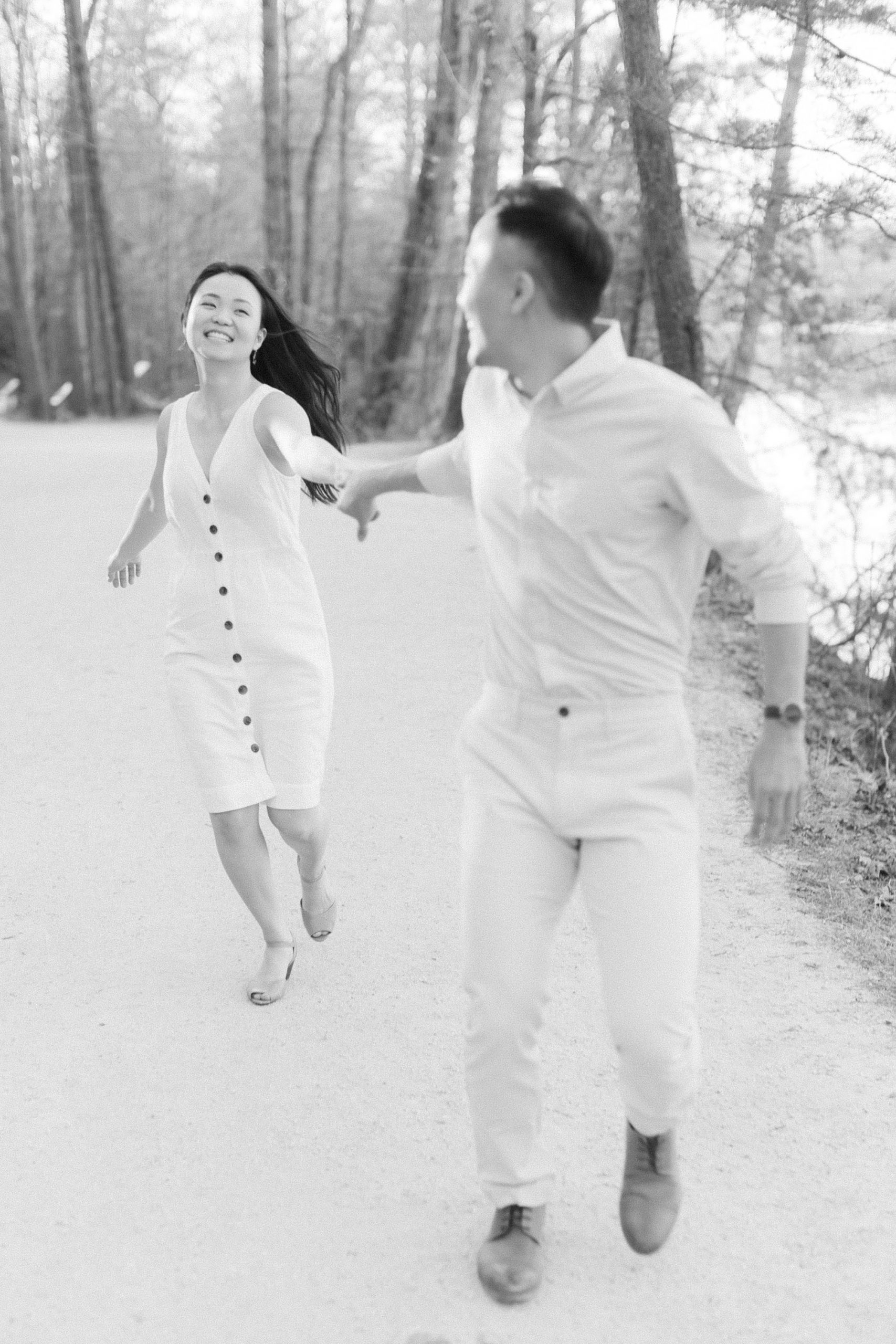 bride and groom laugh, running through park in North Carolina 