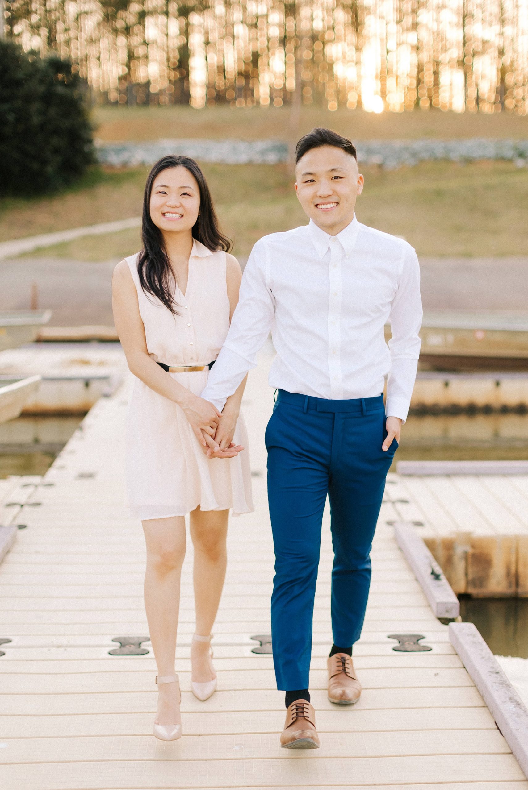 engaged couple holds hands walking on dock