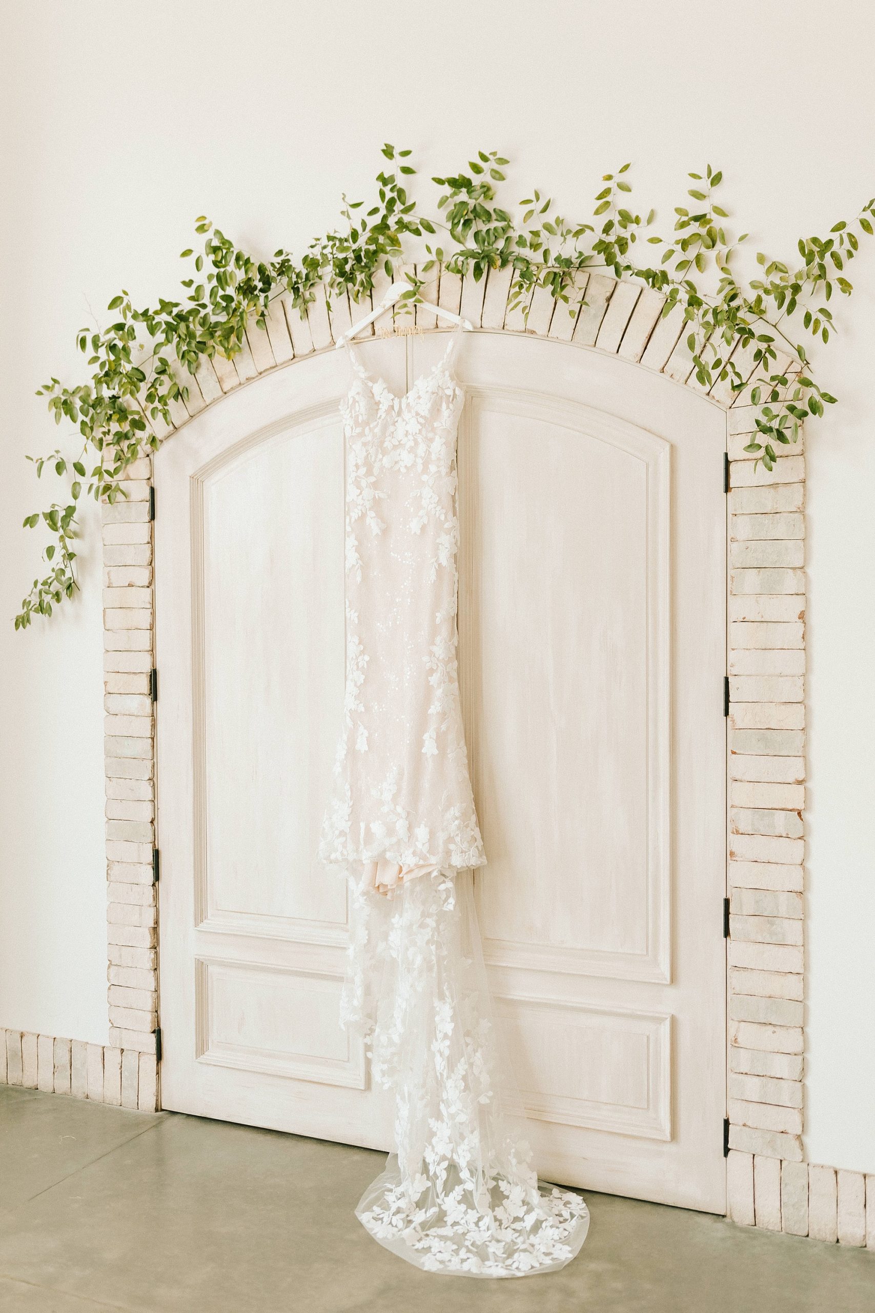 wedding dress hangs on door with greenery