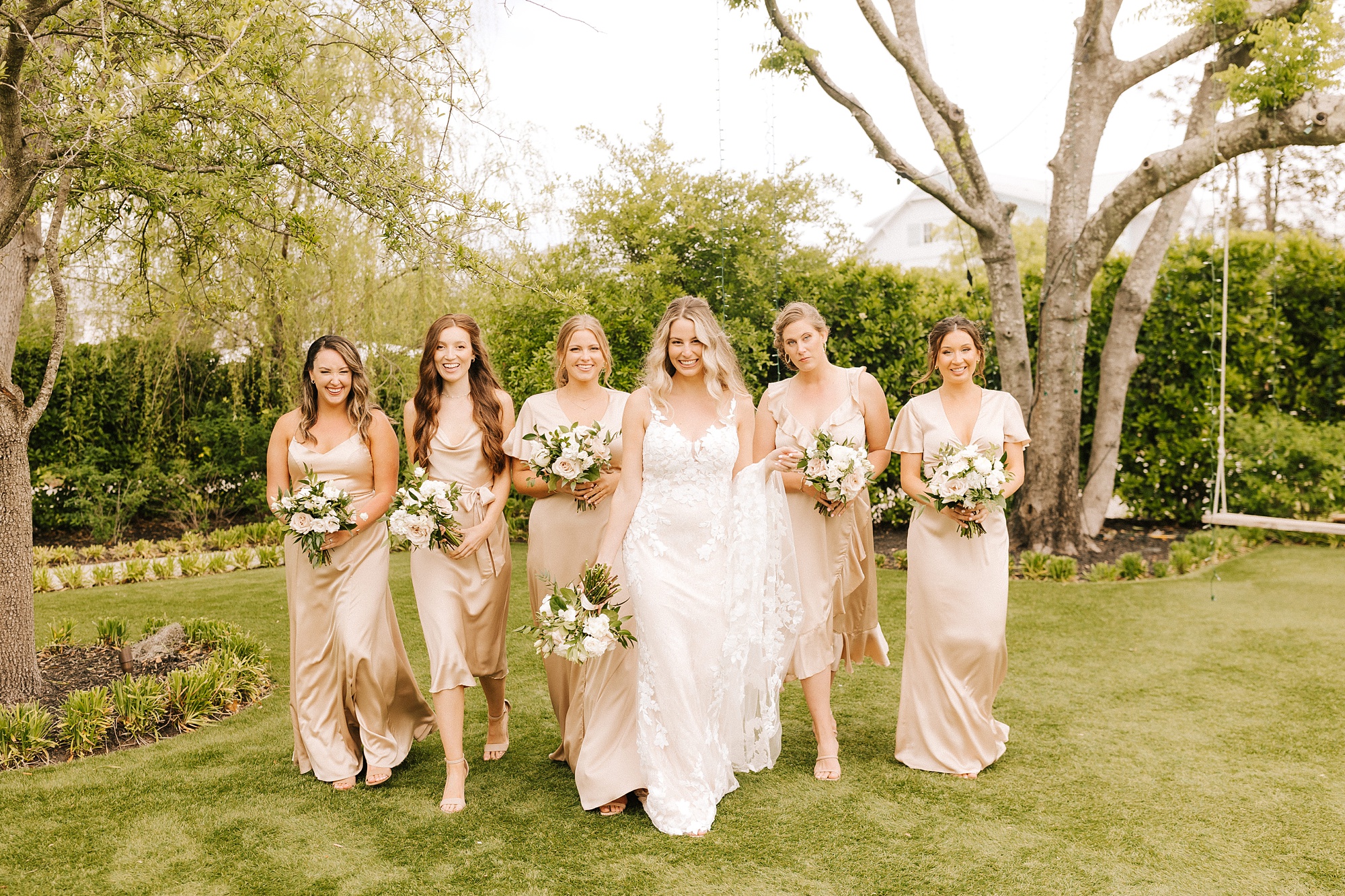 bride walks with bridesmaids in champagne dresses 