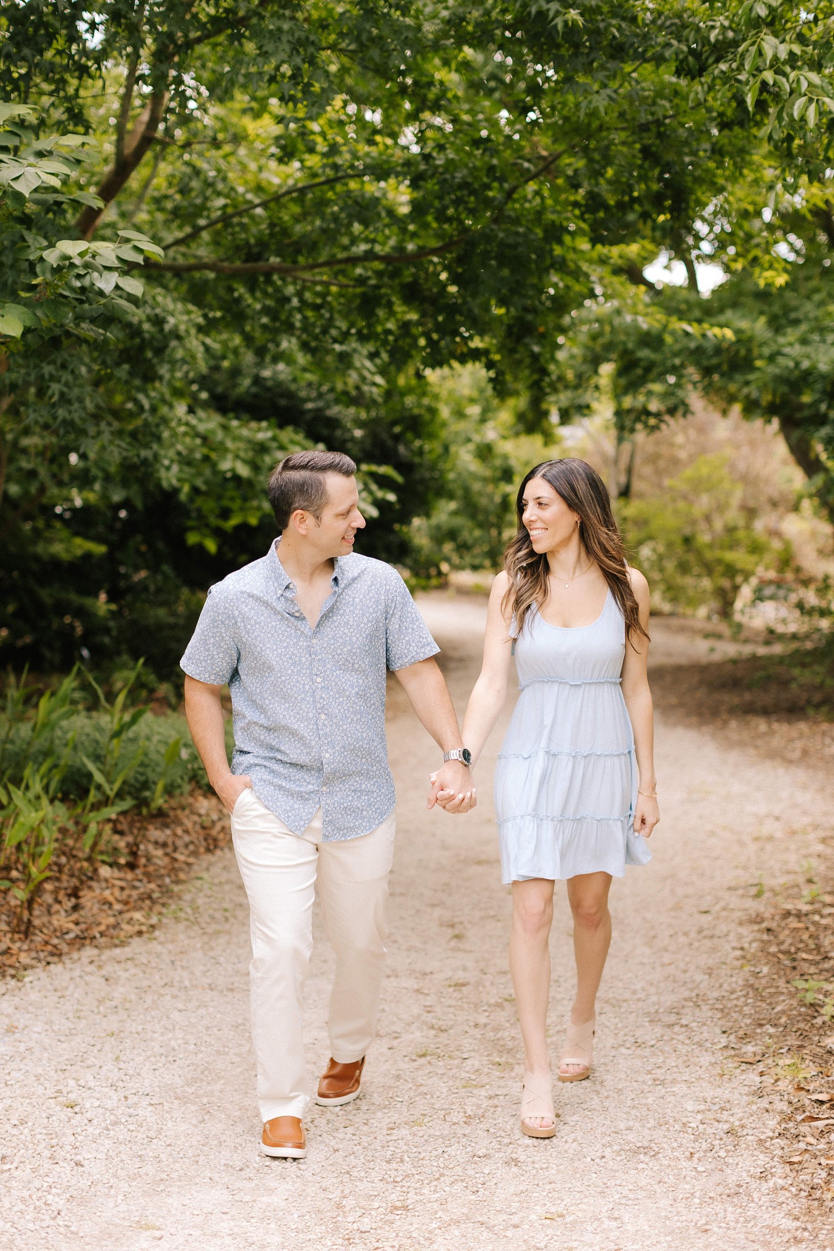couple holds hands walking through Raleigh garden 