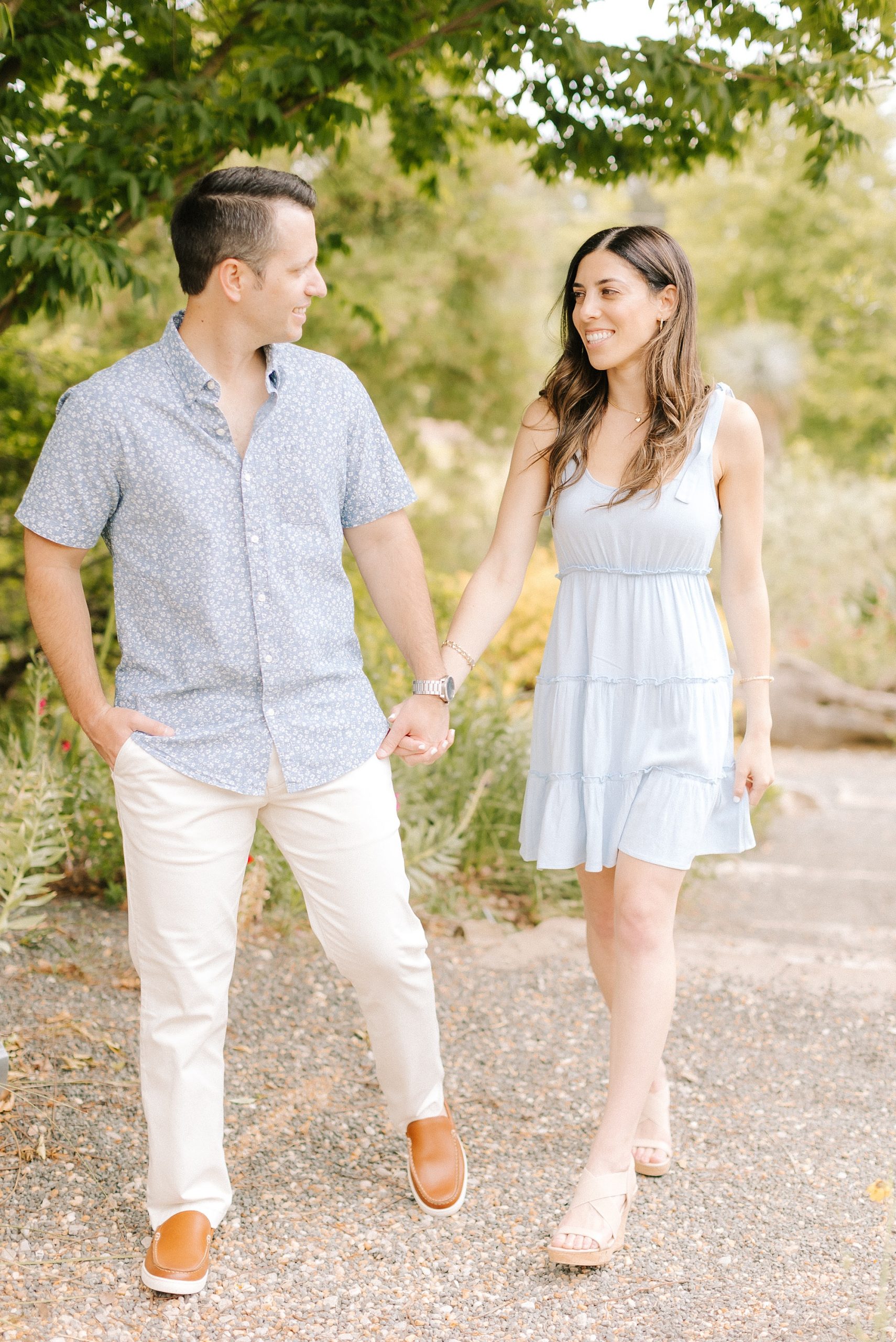 bride and groom walk through JC Raulston Arboretum during engagement photos 