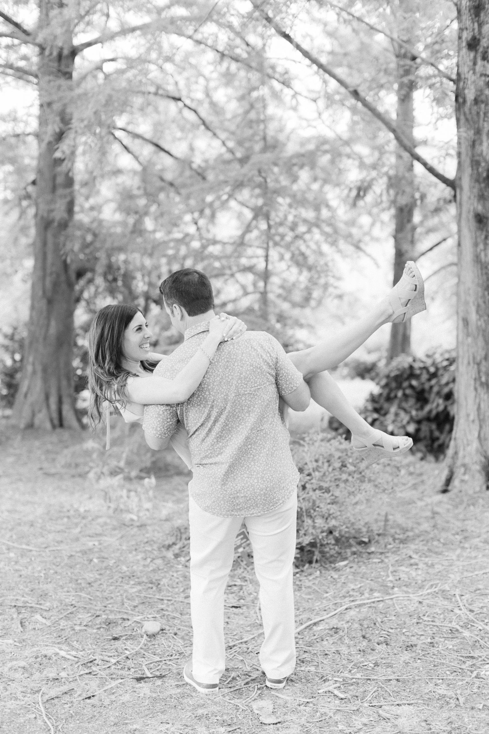 groom lifts bride up while she kicks leg out during spring engagement photos 