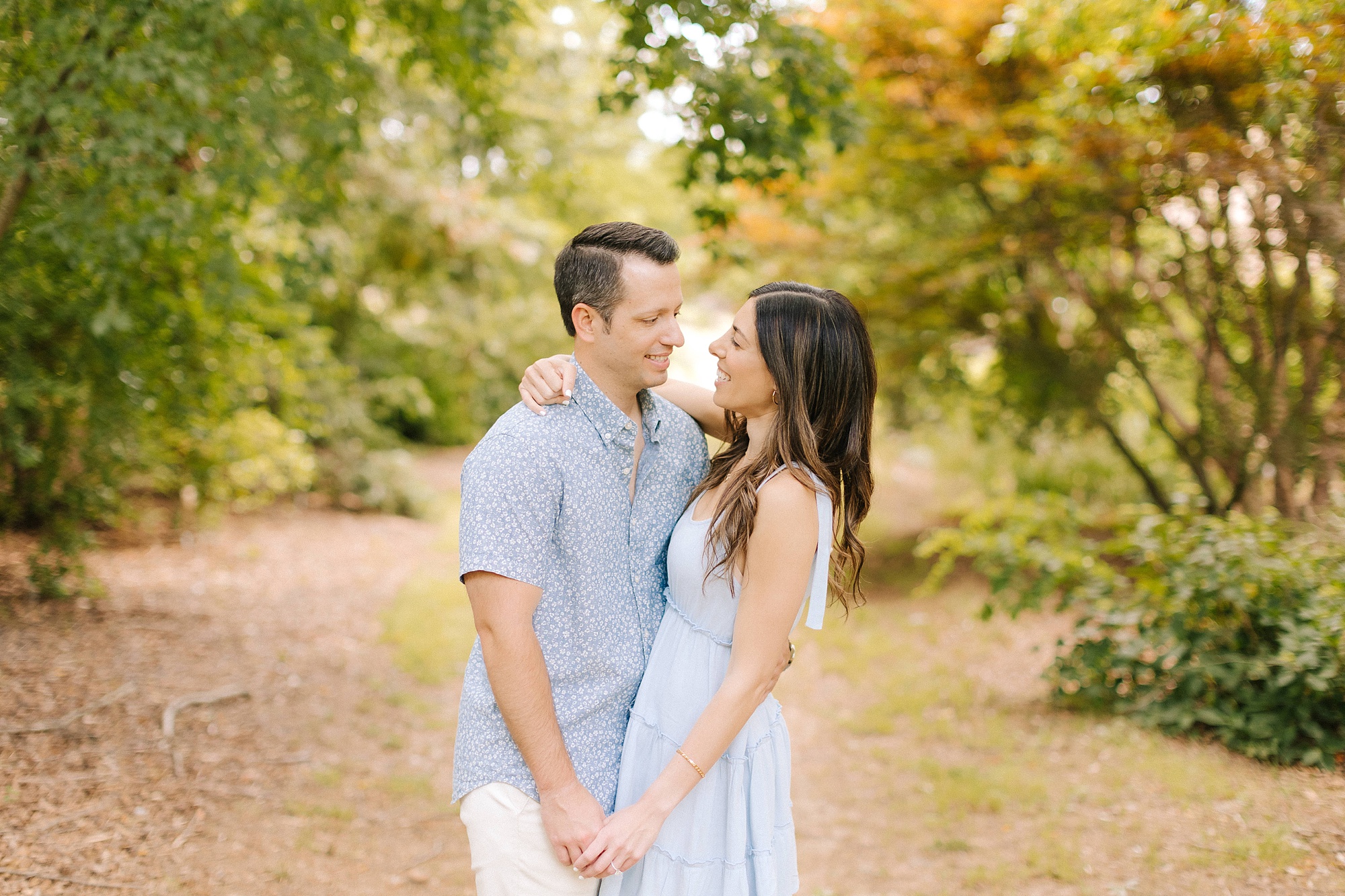bride and groom hold hands looking at each other during Raleigh NC engagement session 