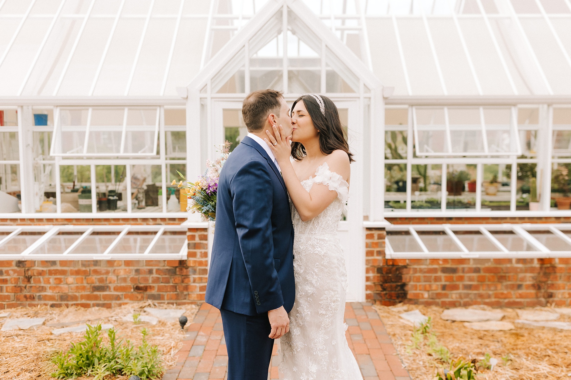 bride kisses groom outside Moore's Spring Manor greenhouse 