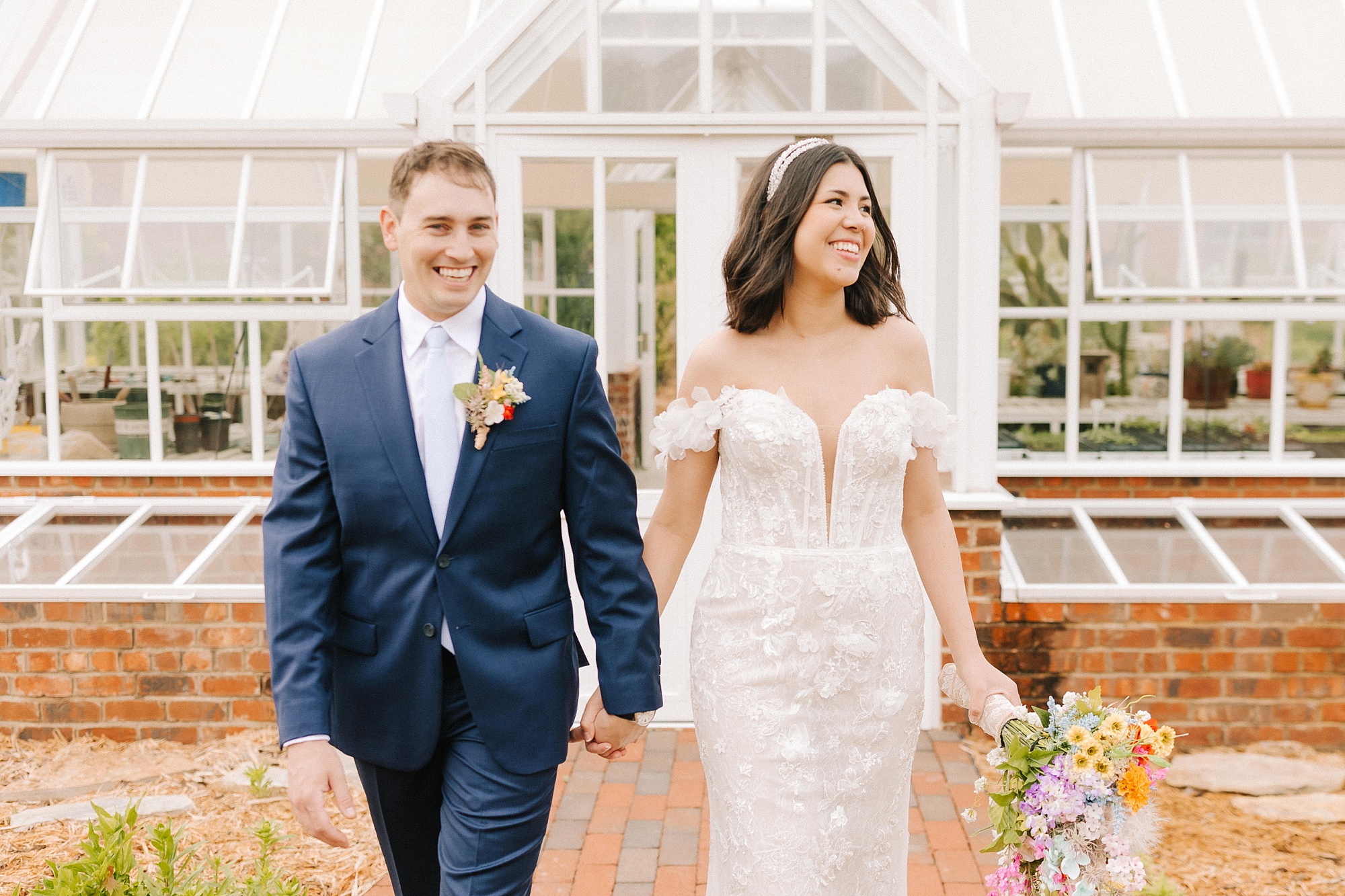 bride and groom walk outside greenhouse