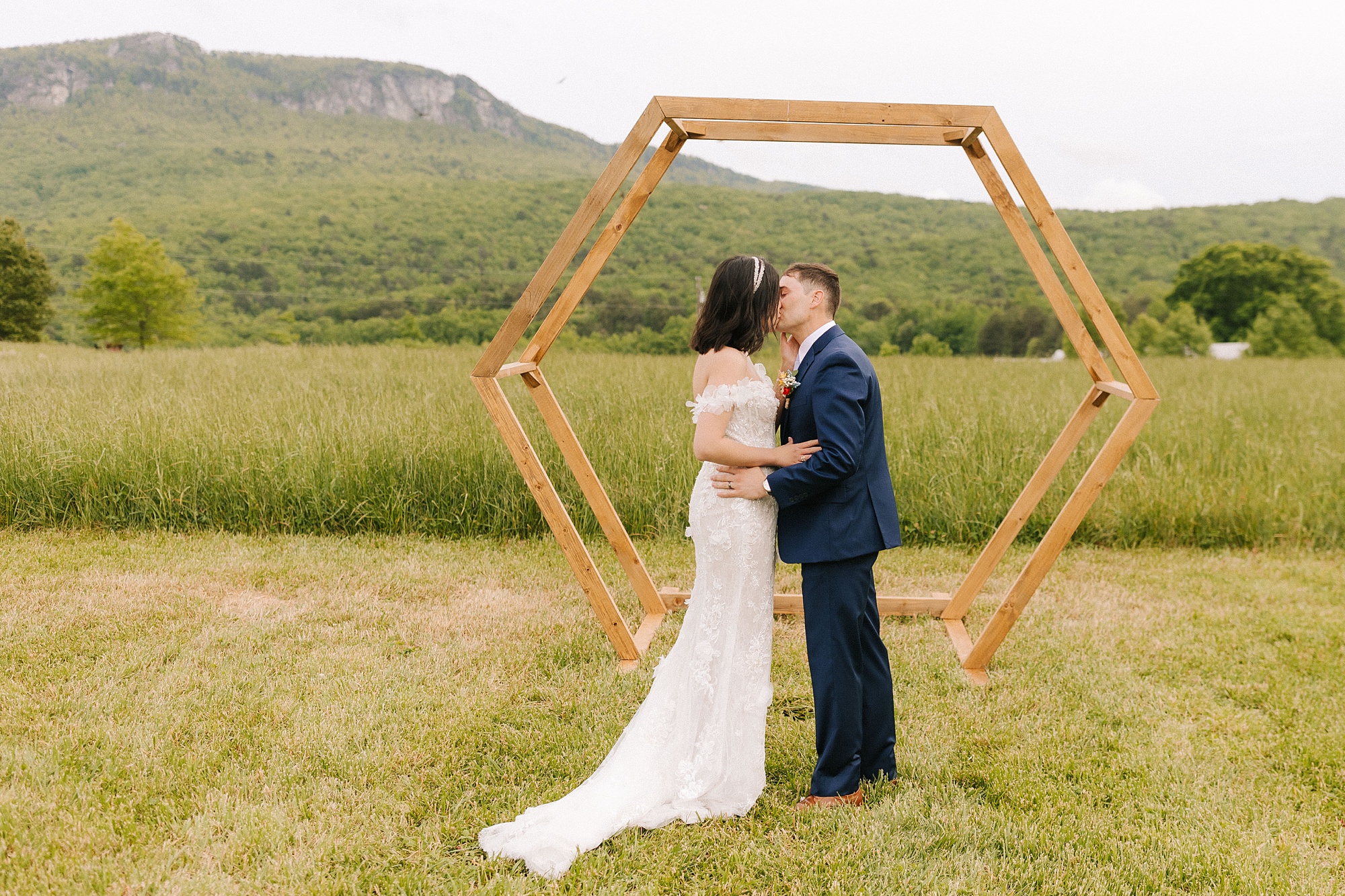 bride and groom kiss by wooden arbor