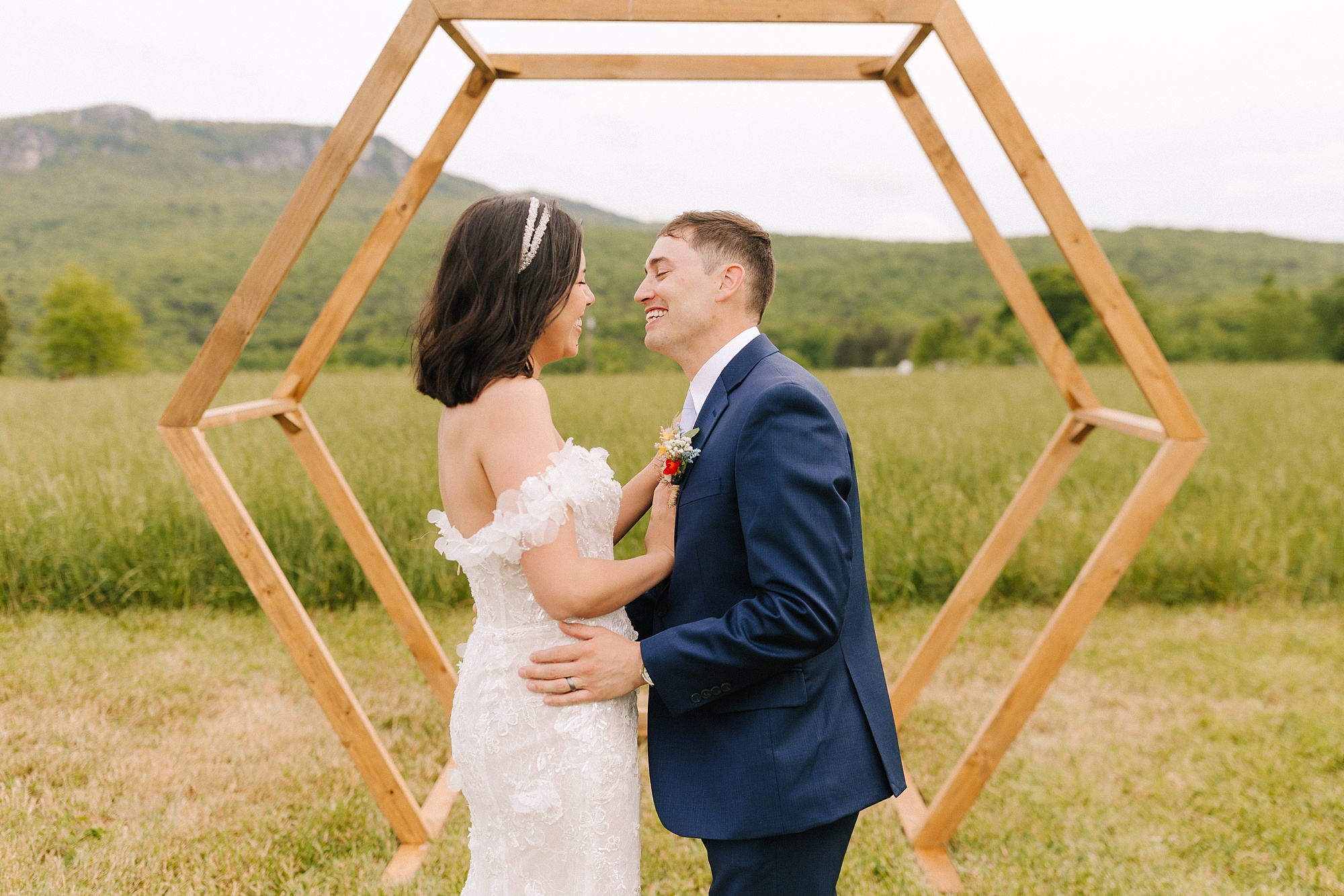 newlyweds smile by wooden arbor