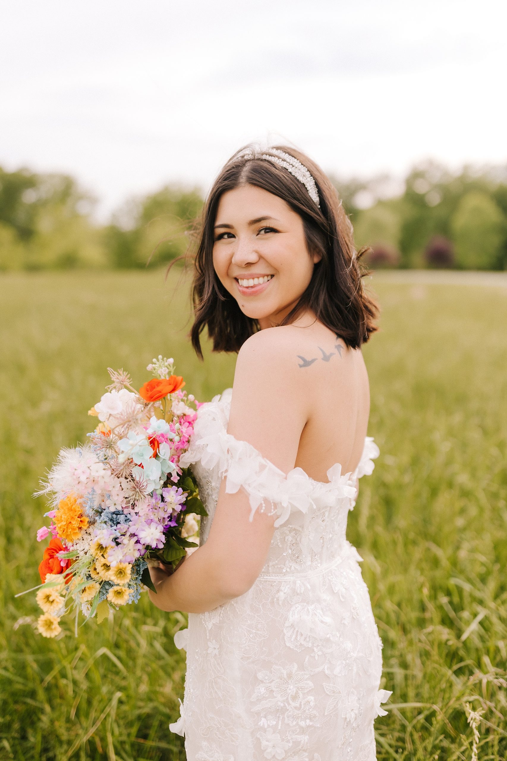 bride looks over shoulder holding bouquet of bright wildflowers 